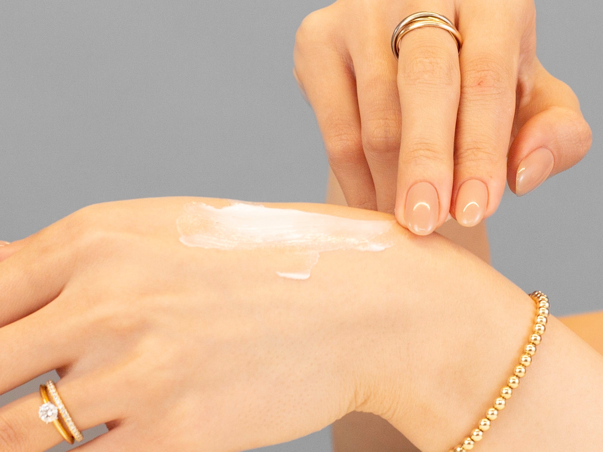 Laziza from LAZ Skincare demonstrating the texture and application of Alastin Ultra Nourishing Moisturizer on her hand