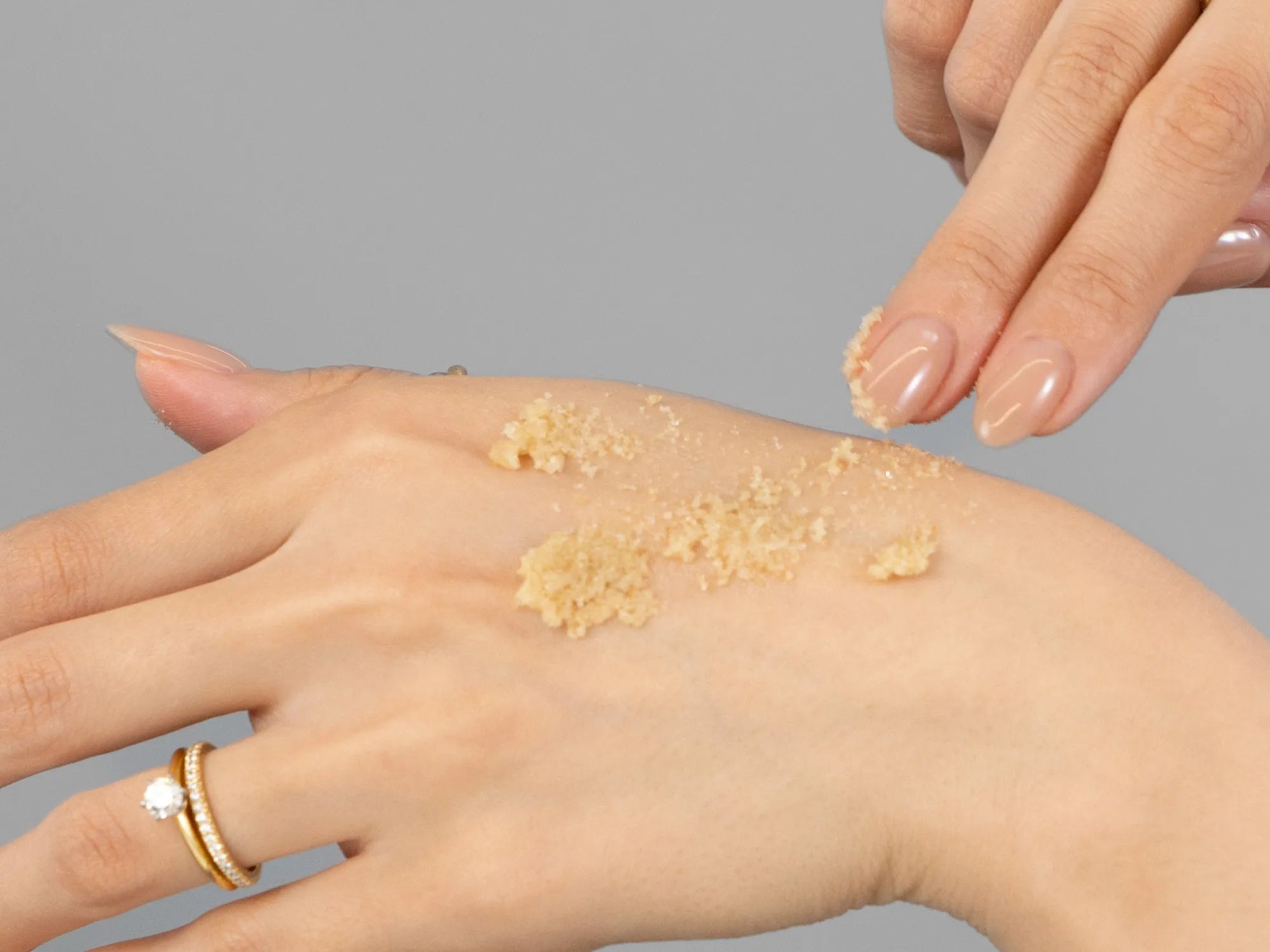 Laziza from LAZ Skincare demonstrating the texture and application of Epicuren Cinnamon Vanilla Brown Sugar Polish on her hand
