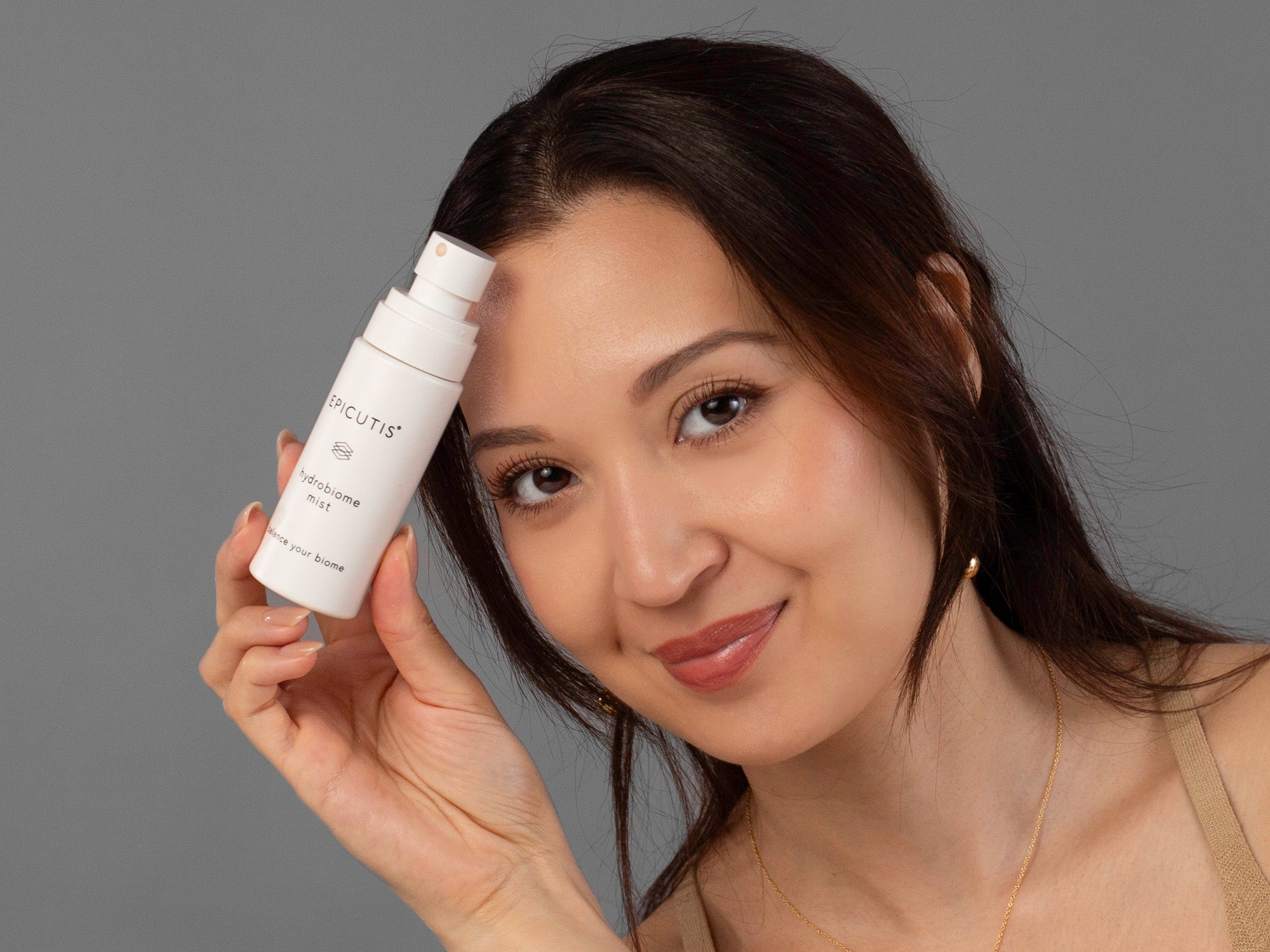 Laziza from LAZ Skincare holding a bottle of Epicutis Hydrobiome Mist up to her face