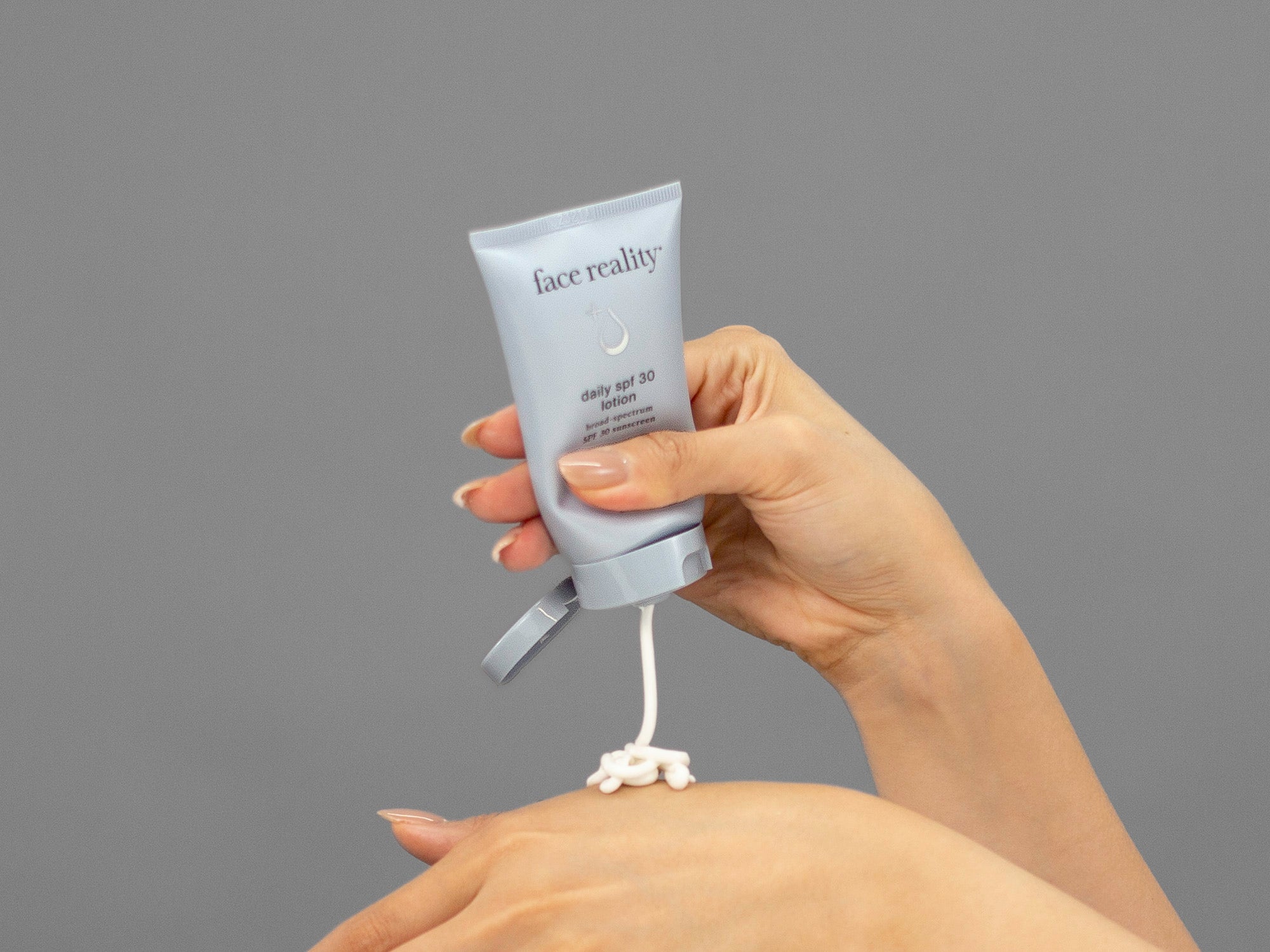 Closeup of Laziza from LAZ Skincare holding up a bottle of Face Reality Daily SPF 30 Plus