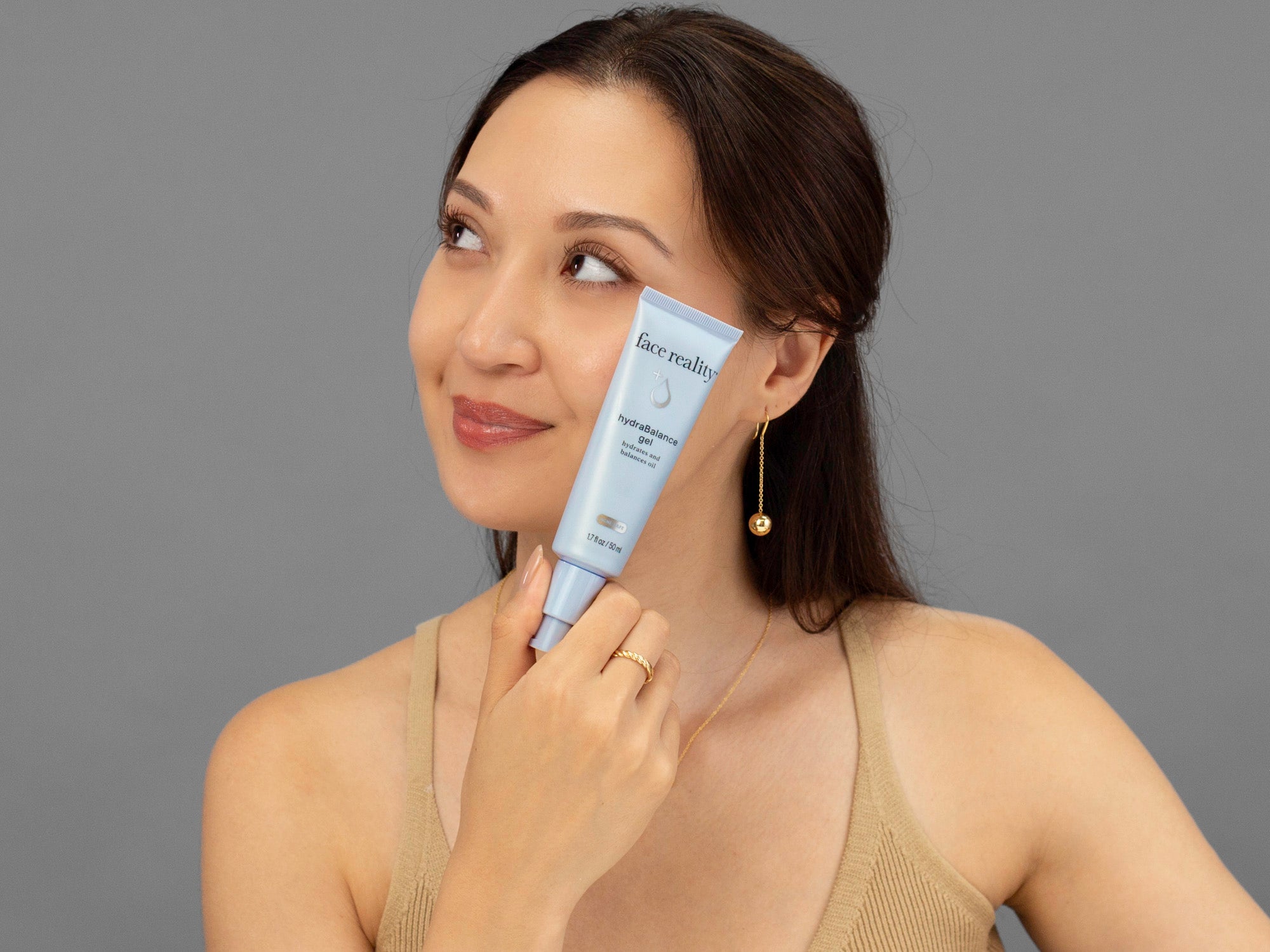 Laziza from LAZ Skincare holding a bottle of Face Reality HydraBalance Gel up to her face