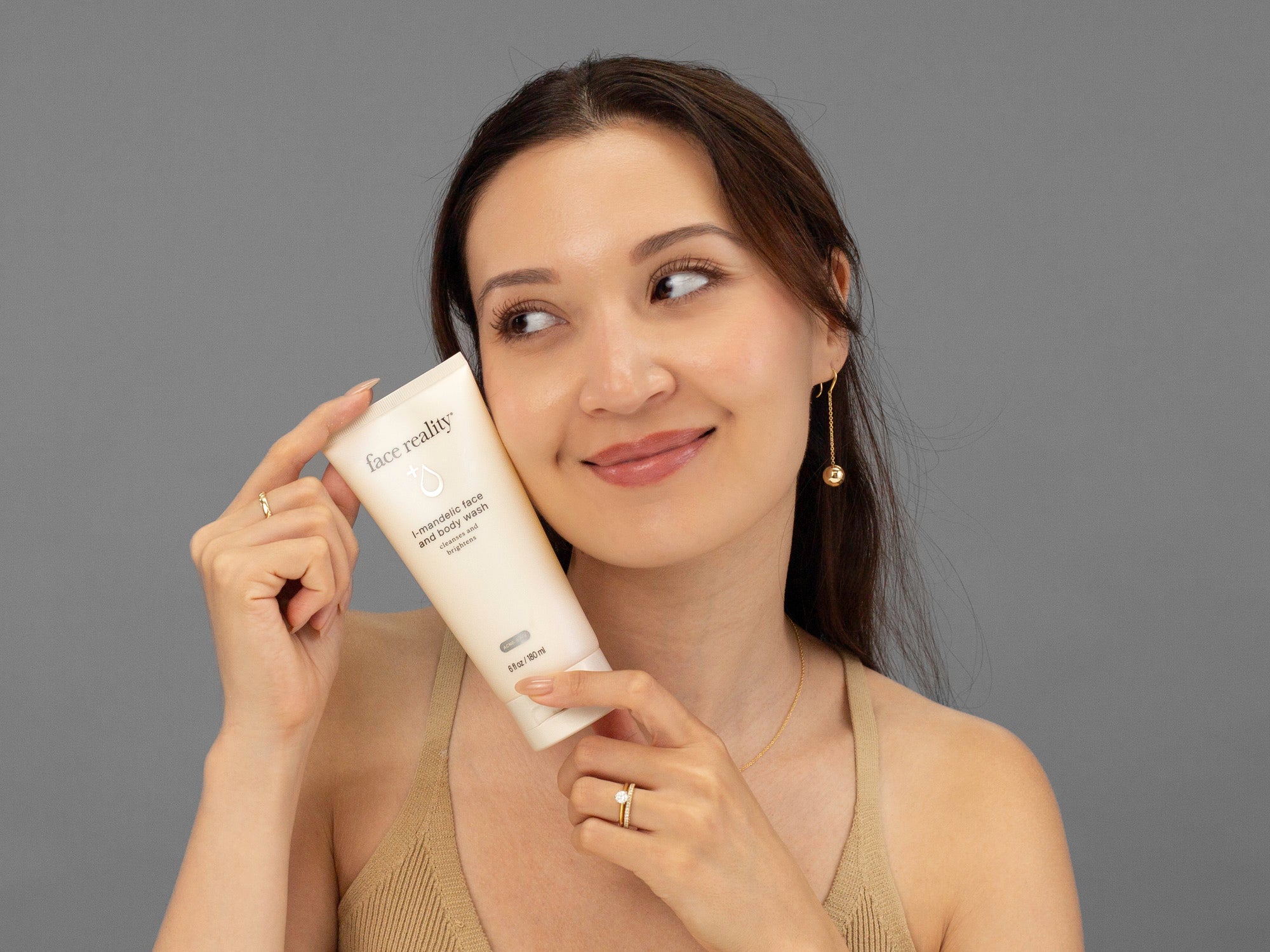 Laziza from LAZ Skincare holding a bottle of Face Reality Mandelic Face & Body Wash up to her face