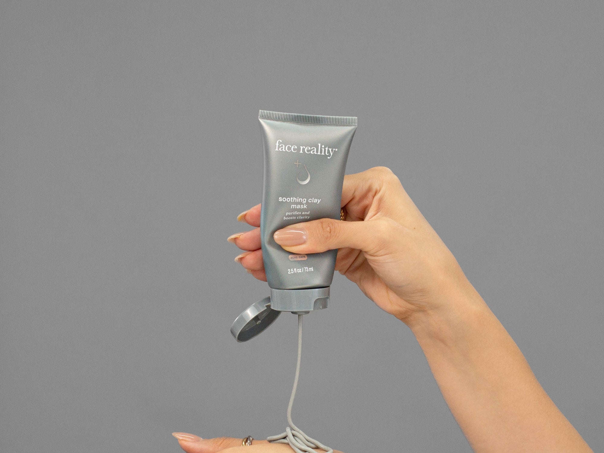 Closeup of Laziza from LAZ Skincare holding up a bottle of Face Reality Soothing Clay Mask
