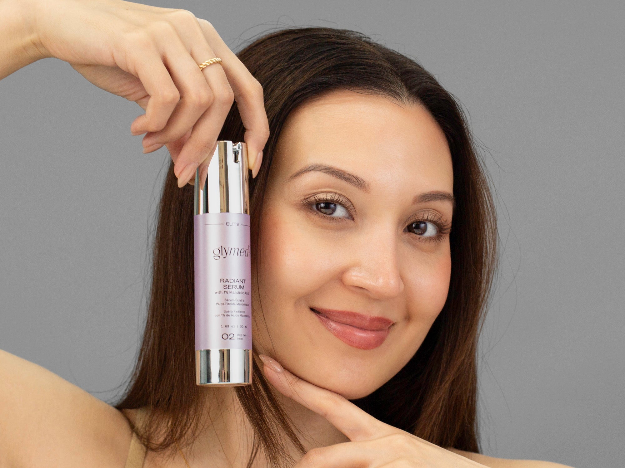 Laziza from LAZ Skincare holding a bottle of GlyMed Radiant Serum up to her face