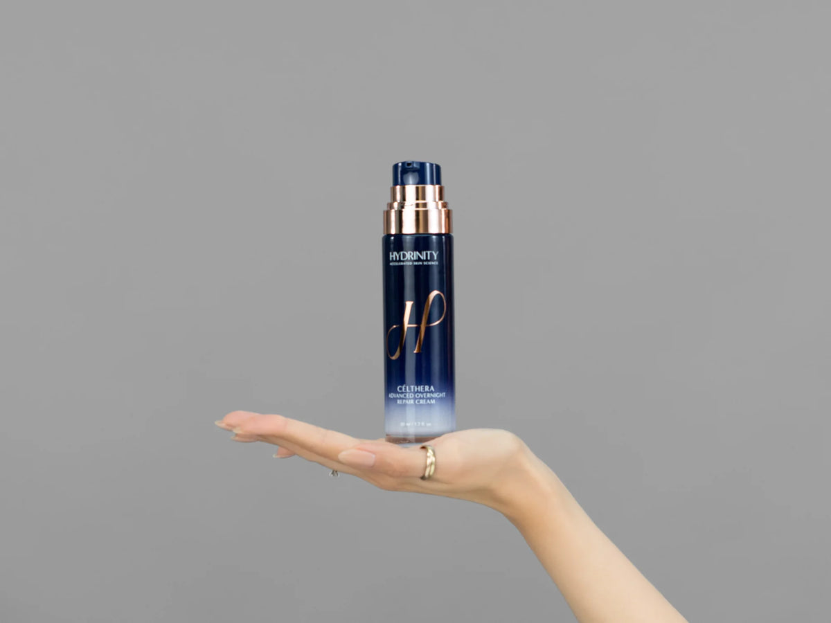 Closeup of Laziza from LAZ Skincare holding up a bottle of Hydrinity CELTHERA Advanced Overnight Repair Cream