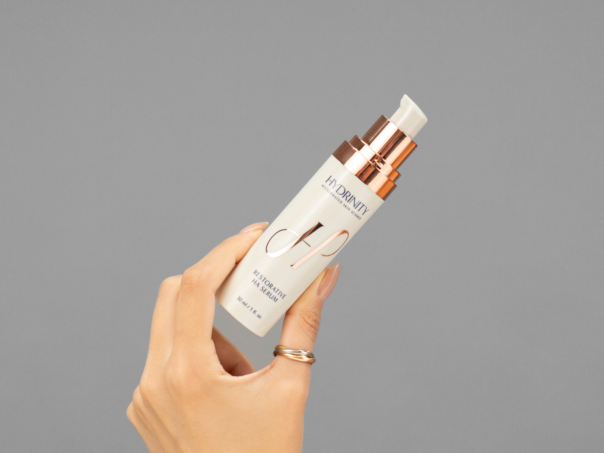 Closeup of Laziza from LAZ Skincare holding a bottle of Hydrinity Resorative HA Serum in her hand