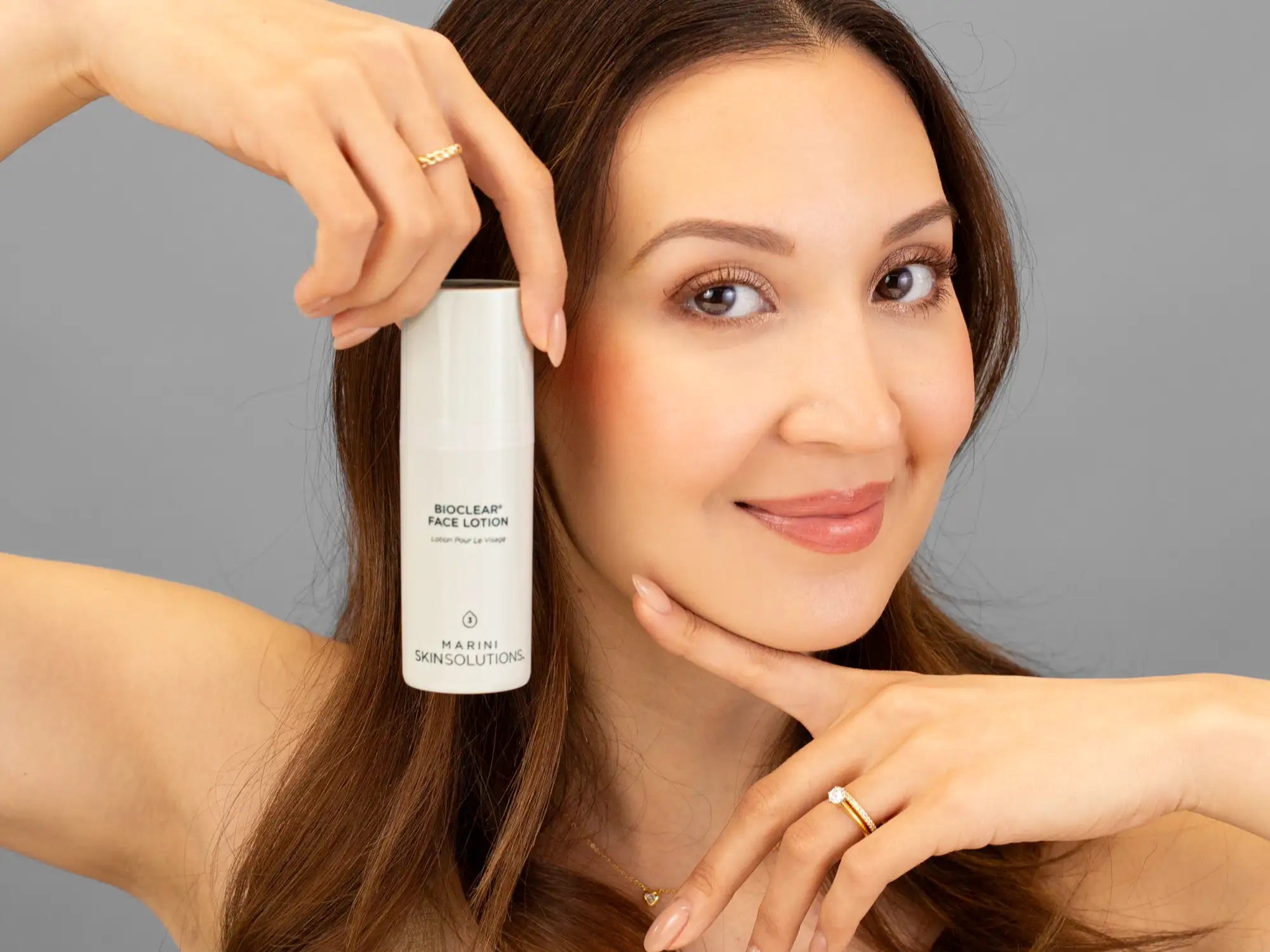 Laziza from LAZ Skincare holding a bottle of Marini SkinSolutions Bioclear Face Lotion up to her face