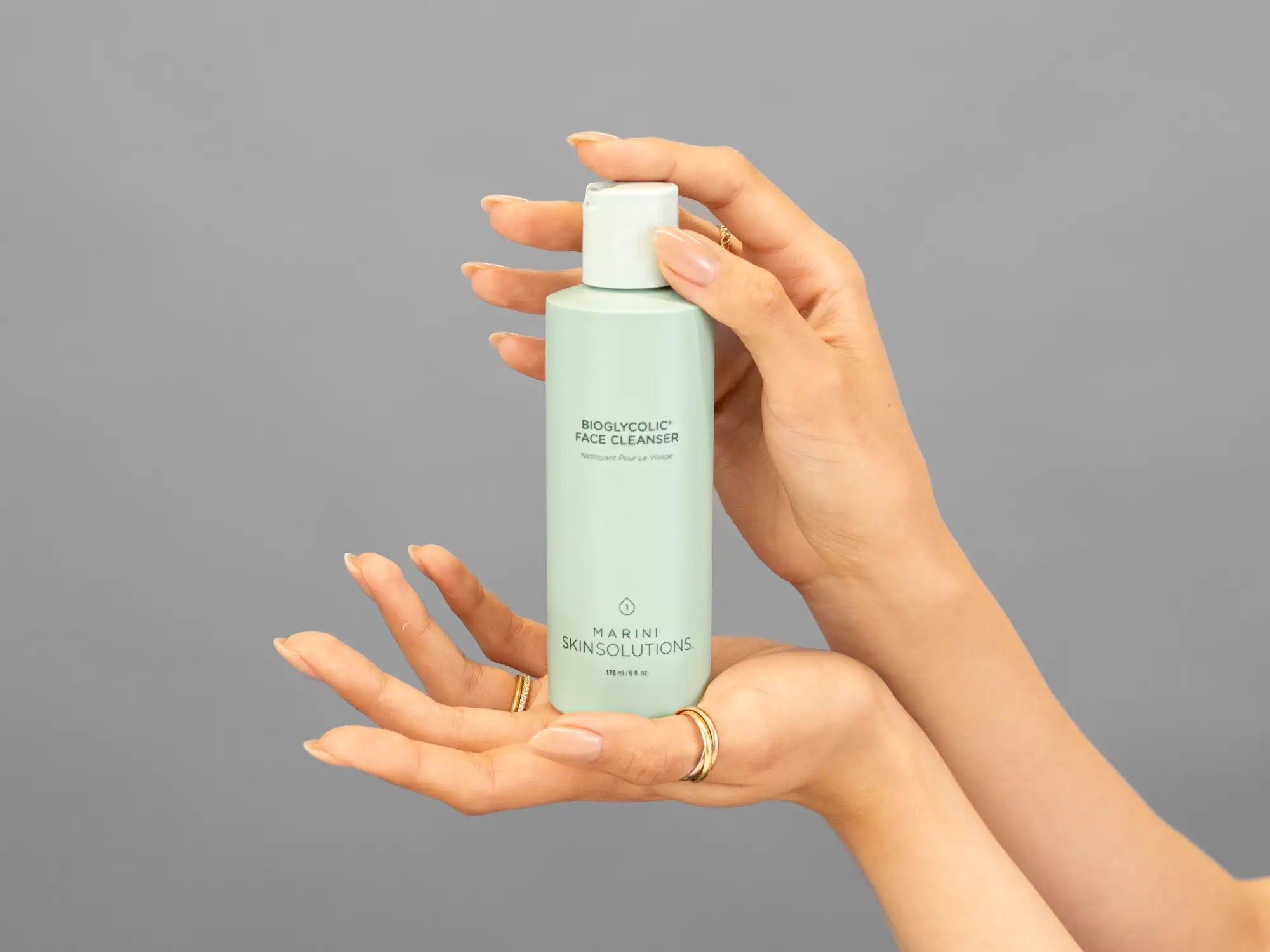 Closeup of Laziza from LAZ Skincare holding up a bottle of Marini SkinSolutions Bioglycolic Face Cleanser