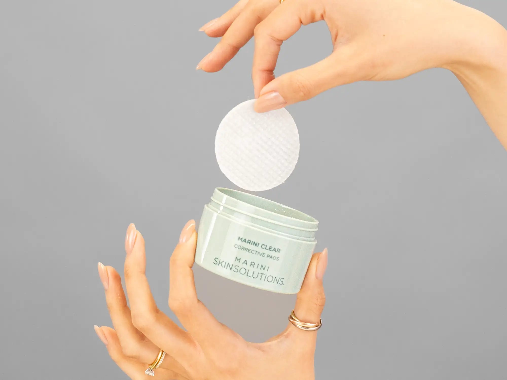 Closeup of Laziza from LAZ Skincare holding up a bottle of Marini SkinSolutions Marini Clear Corrective Pads