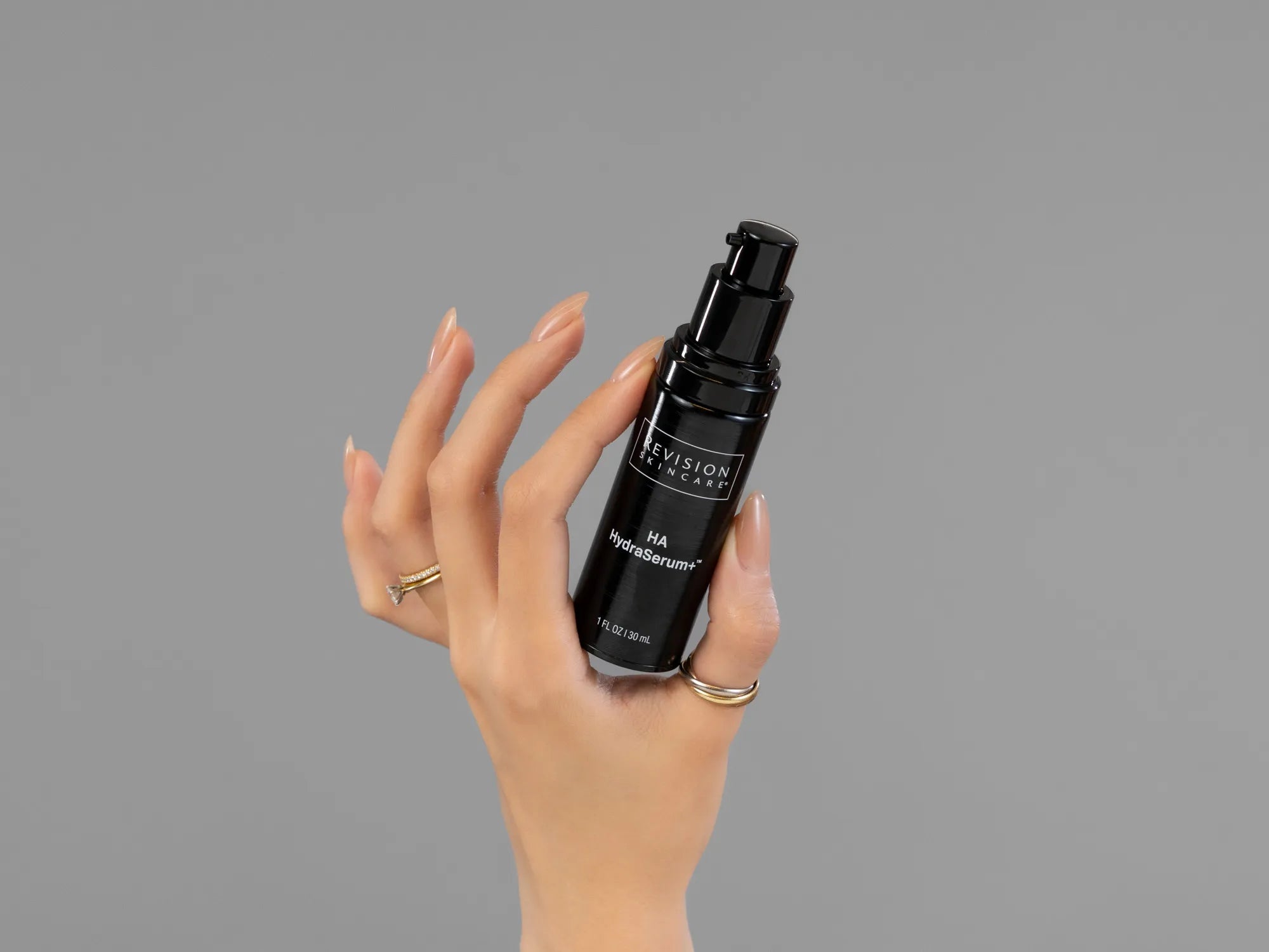 Closeup of Laziza from LAZ Skincare holding up a bottle of Revision HA HydraSerum+