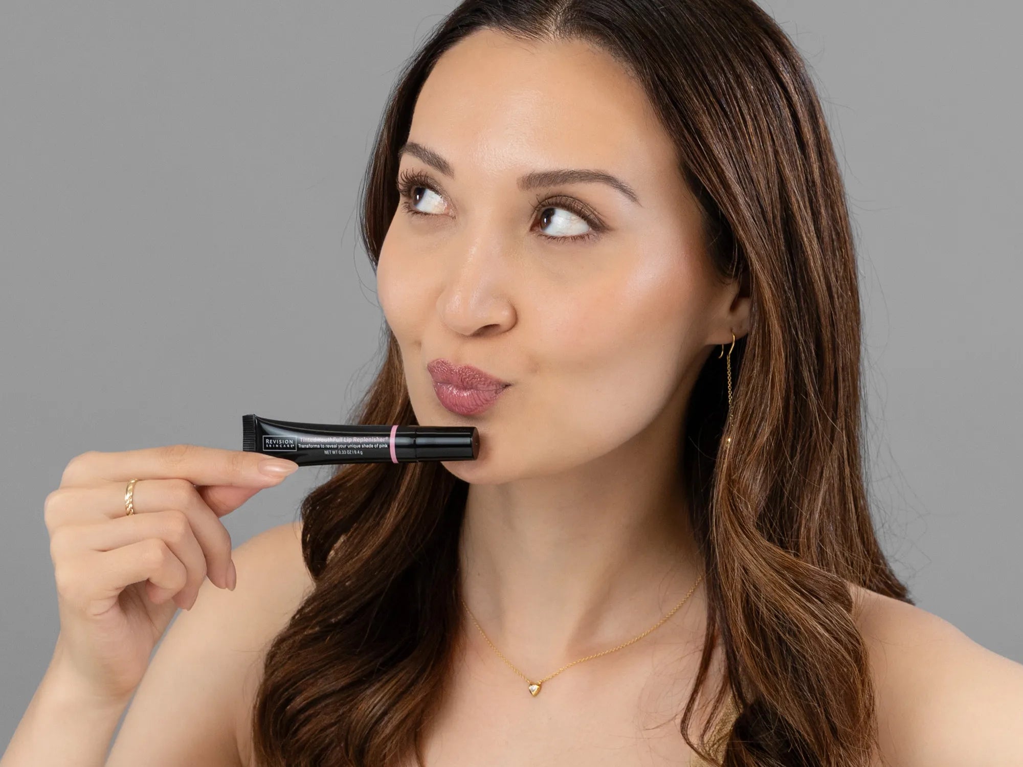 Closeup of Laziza from LAZ Skincare holding up a bottle of Revision Youthfull Lip Replenisher