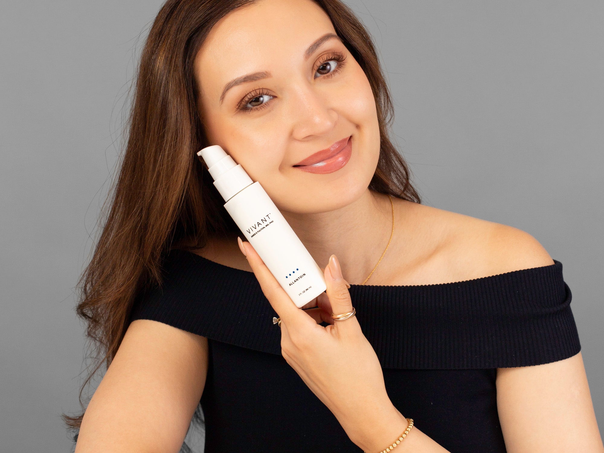 Laziza from LAZ Skincare holding a bottle of Vivant Allantoin up to her face
