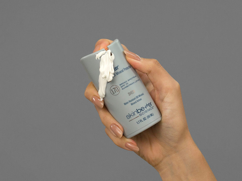 Closeup of Laziza from LAZ Skincare holding up a bottle of SkinBetter Science sunbetter SHEER SPF 70 Sunscreen Lotion