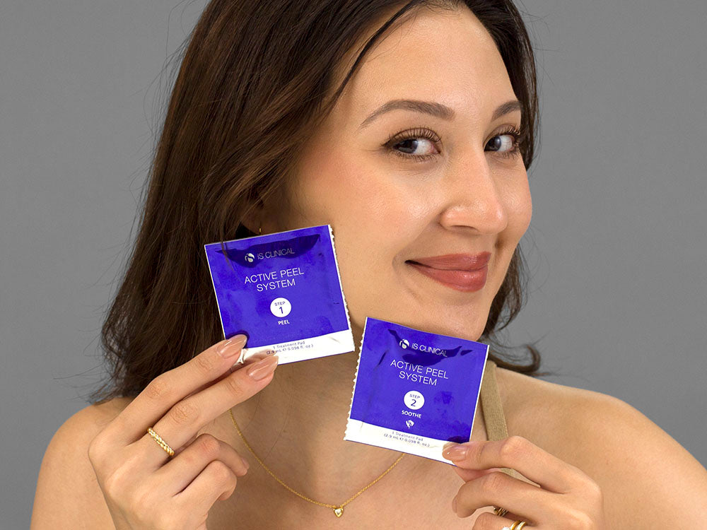 Laziza from LAZ Skincare holding a bottle of iS Clinical Active Peel System up to her face