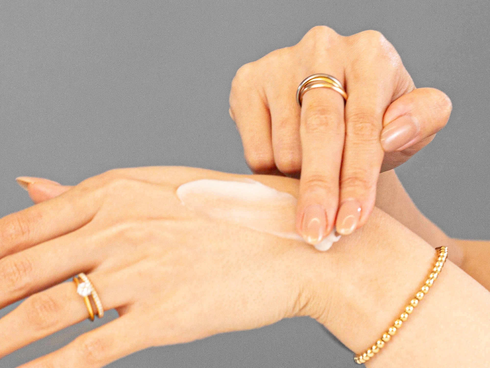 Laziza from LAZ Skincare applying Adipeau Strength Gel to her hand on a neutral background