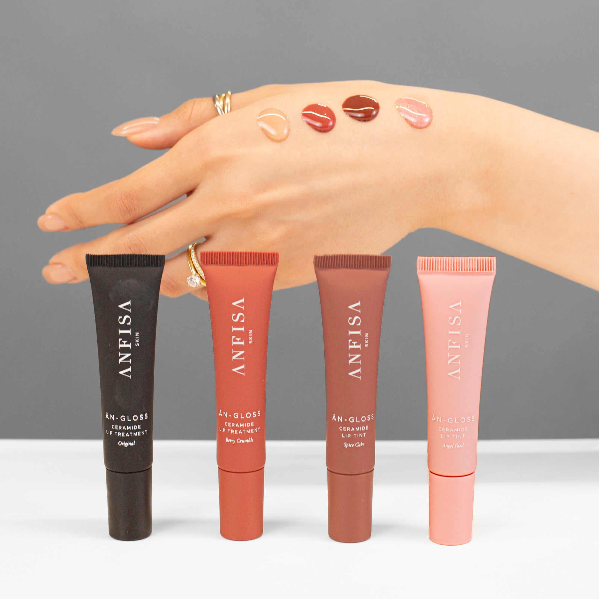 Anfisa An-Gloss product shot showing all 4 tubes and products on skin