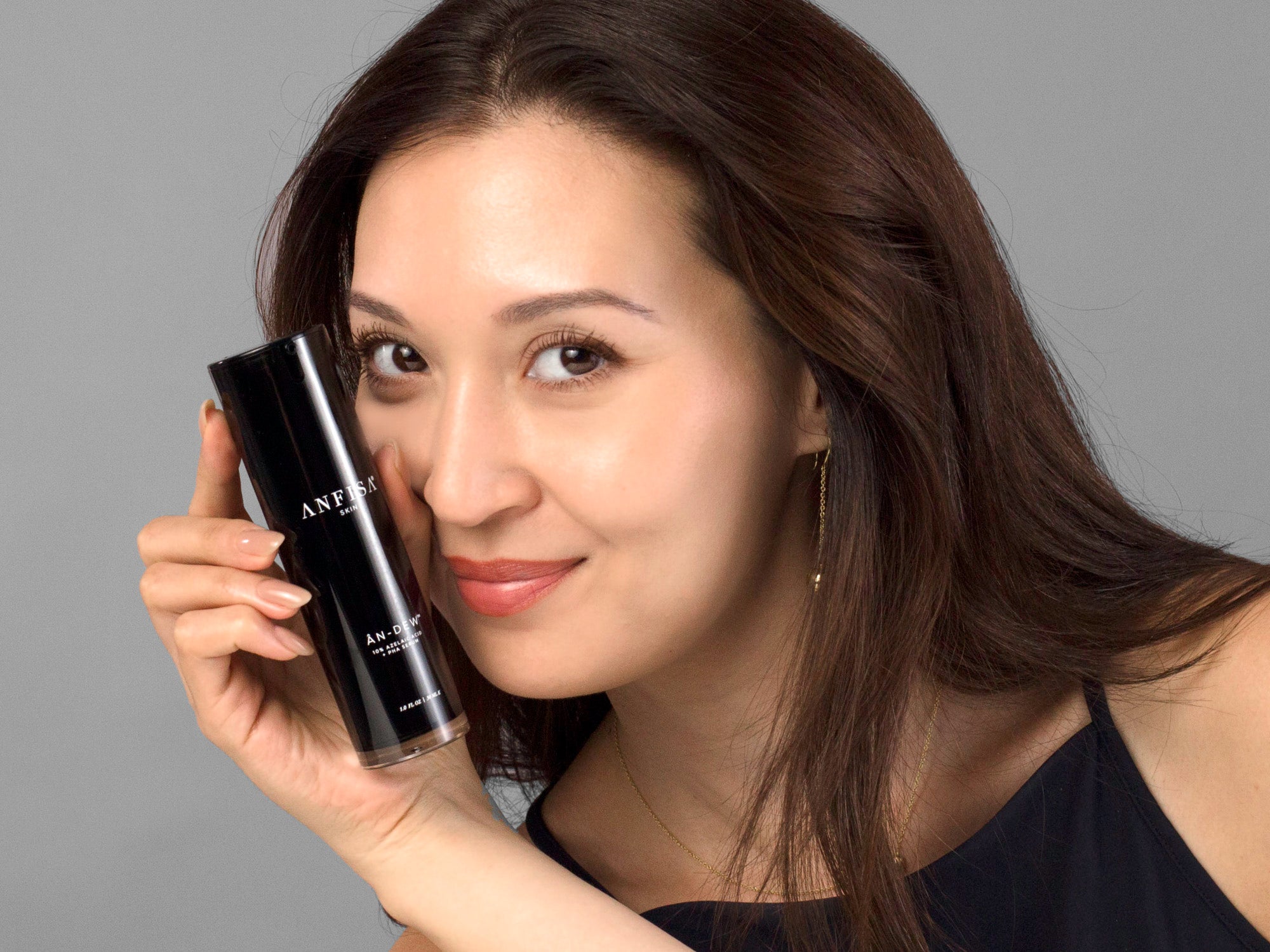Laziza from LAZ Skincare holding a bottle of Anfisa AN-DEW up to her face