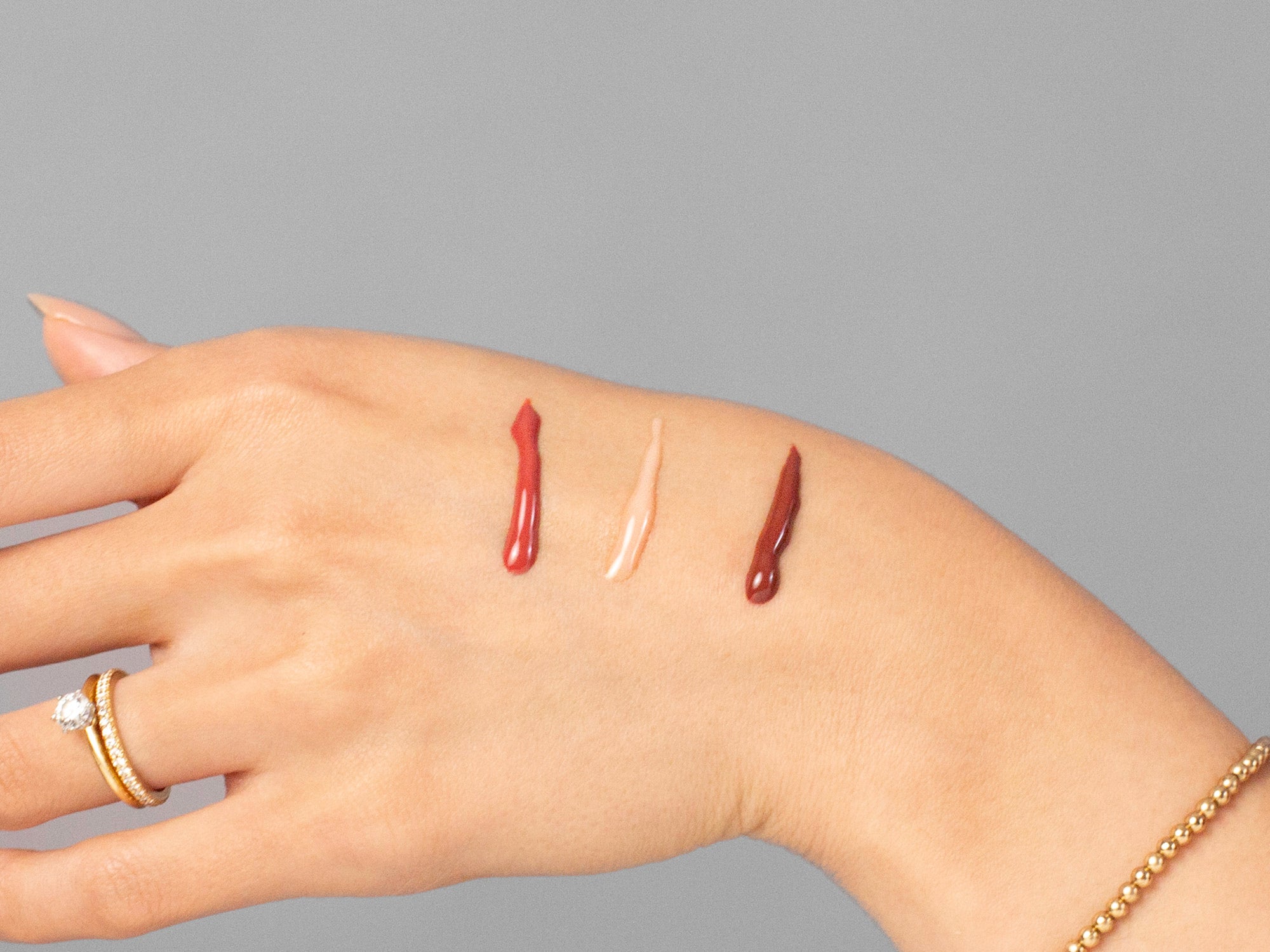 Closeup of Laziza from LAZ Skincare applying 3 different colors of Anfisa AN-GLOSS to her hand