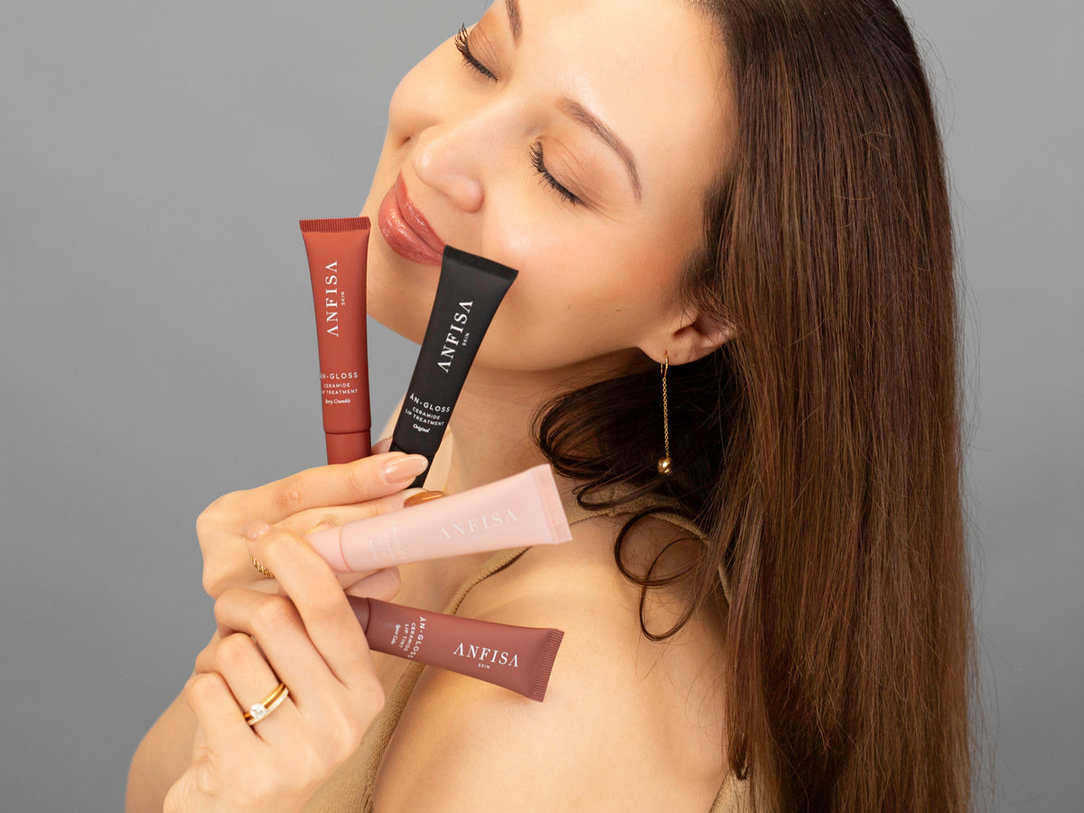 Laziza from LAZ Skincare holding a bottle of Anfisa ÂN-GLOSS up to her face