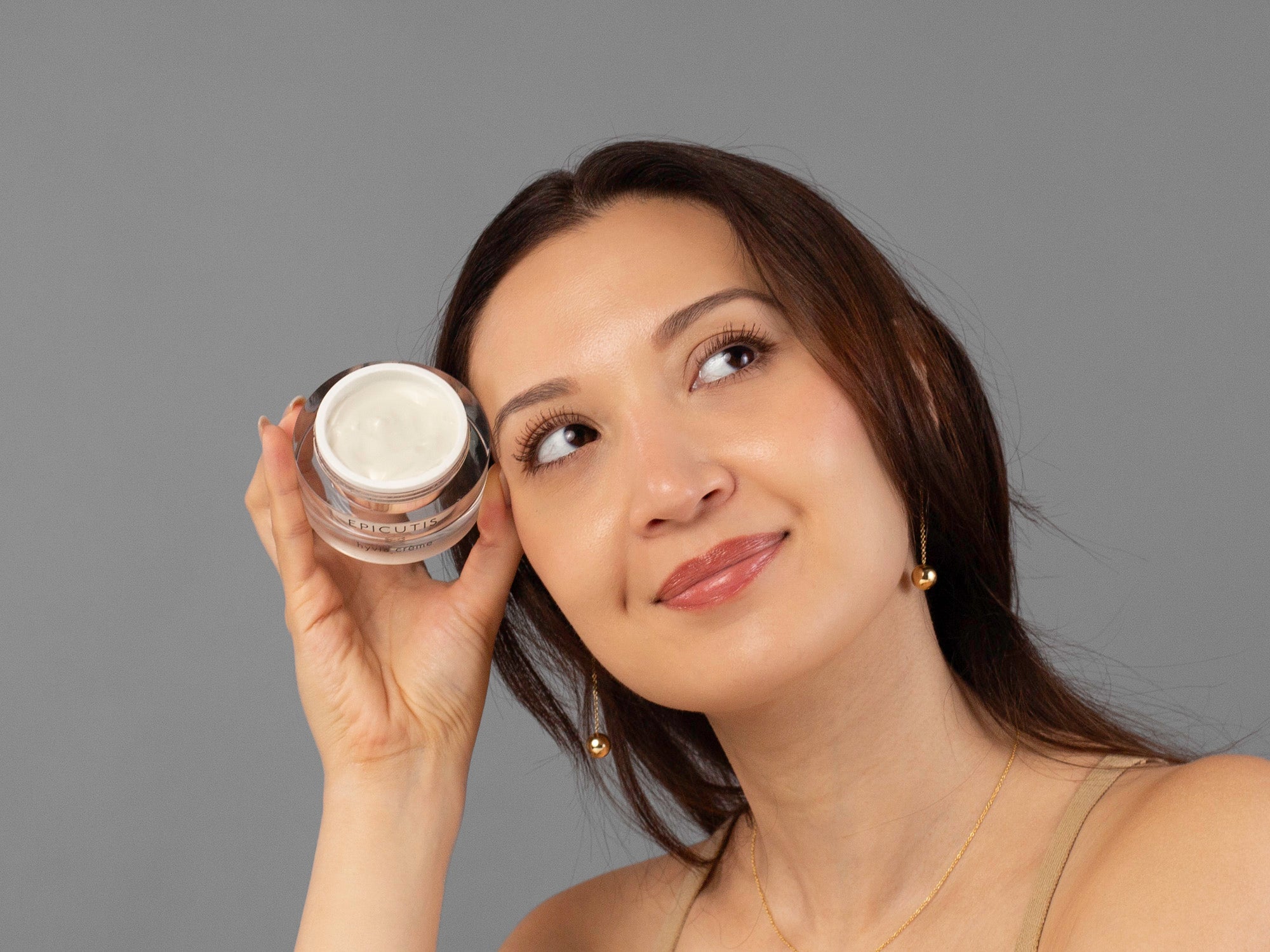 Laziza from LAZ Skincare holding a tub of Epicutis Hyvia Creme up to her face