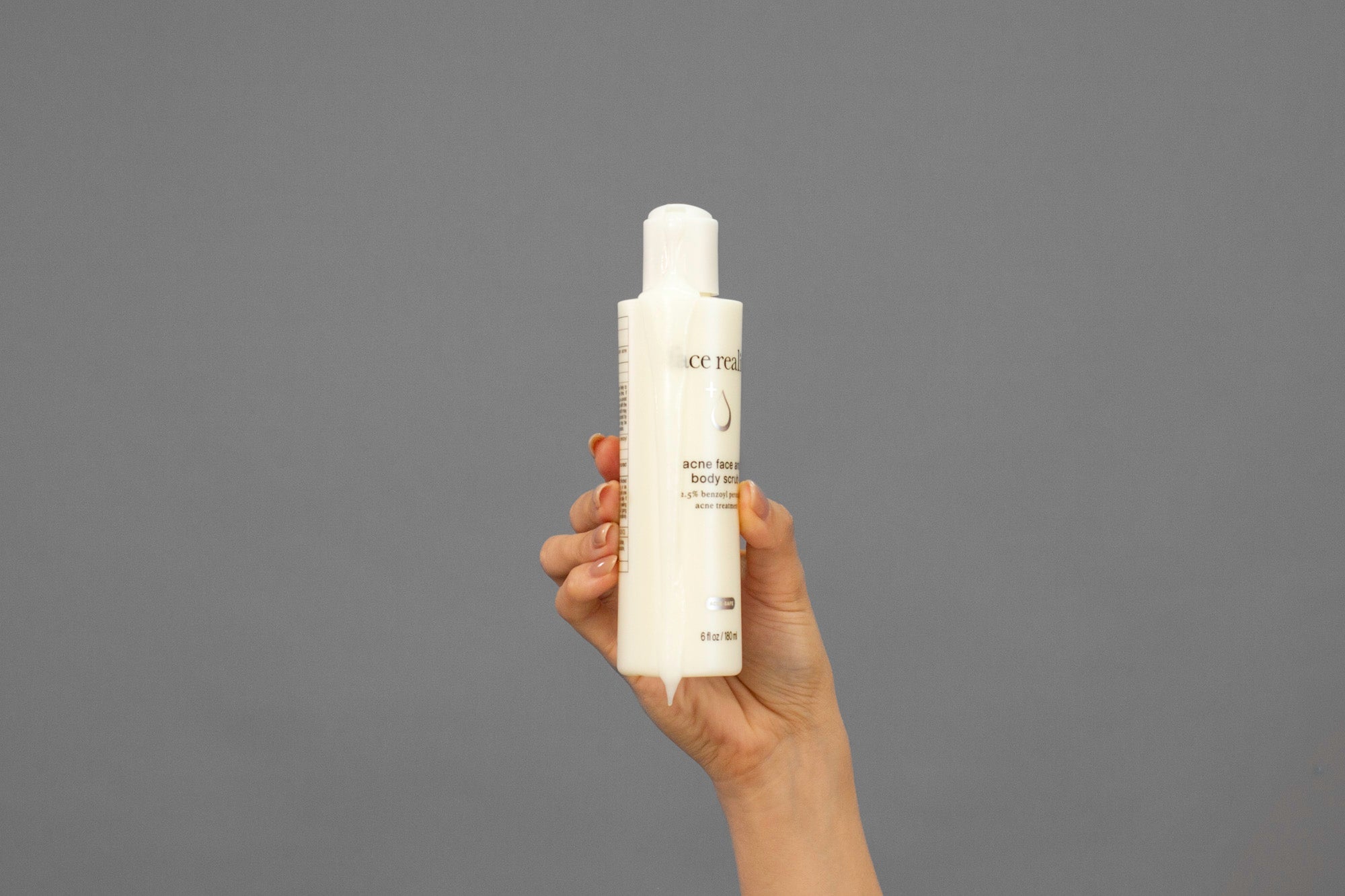 Closeup of Laziza from LAZ Skincare squeezing a bottle of Face Reality Acne Face & Body Scrub