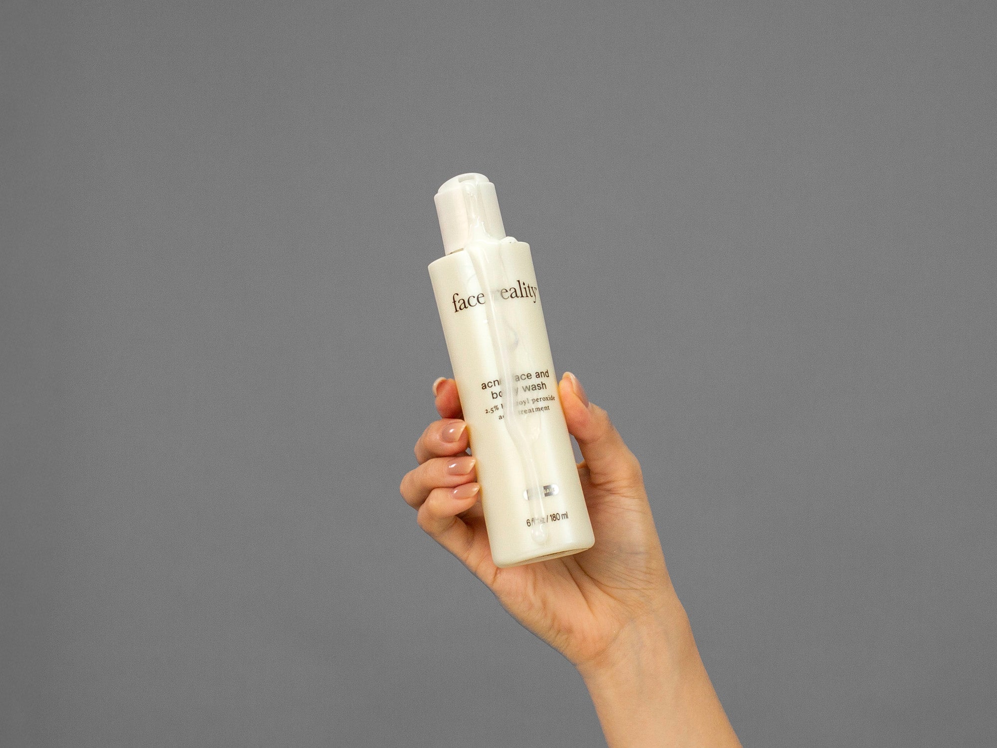 Closeup of Laziza from LAZ Skincare holding up a bottle of Face Reality Acne Face & Body Wash