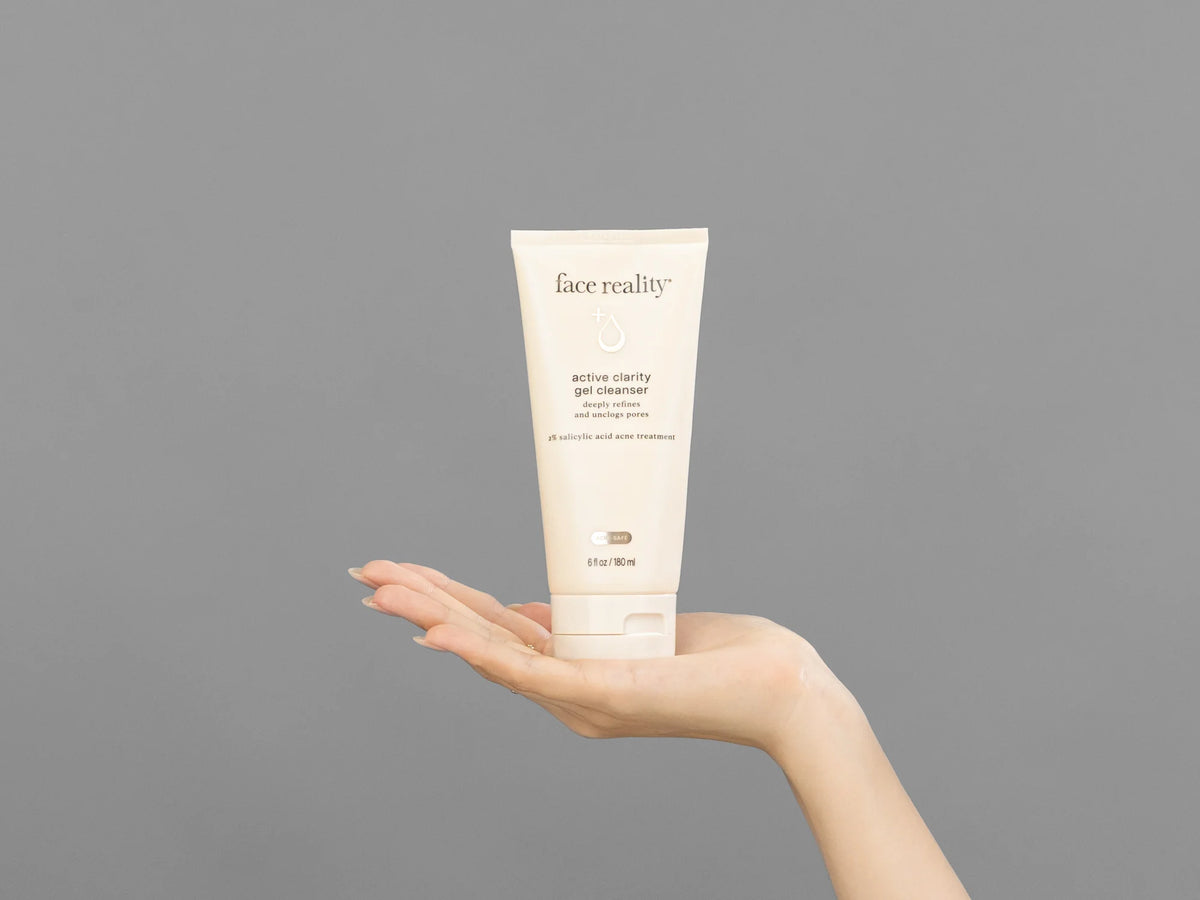 Closeup of Laziza from LAZ Skincare holding up a bottle of Face Reality Active Clarity Gel Cleanser