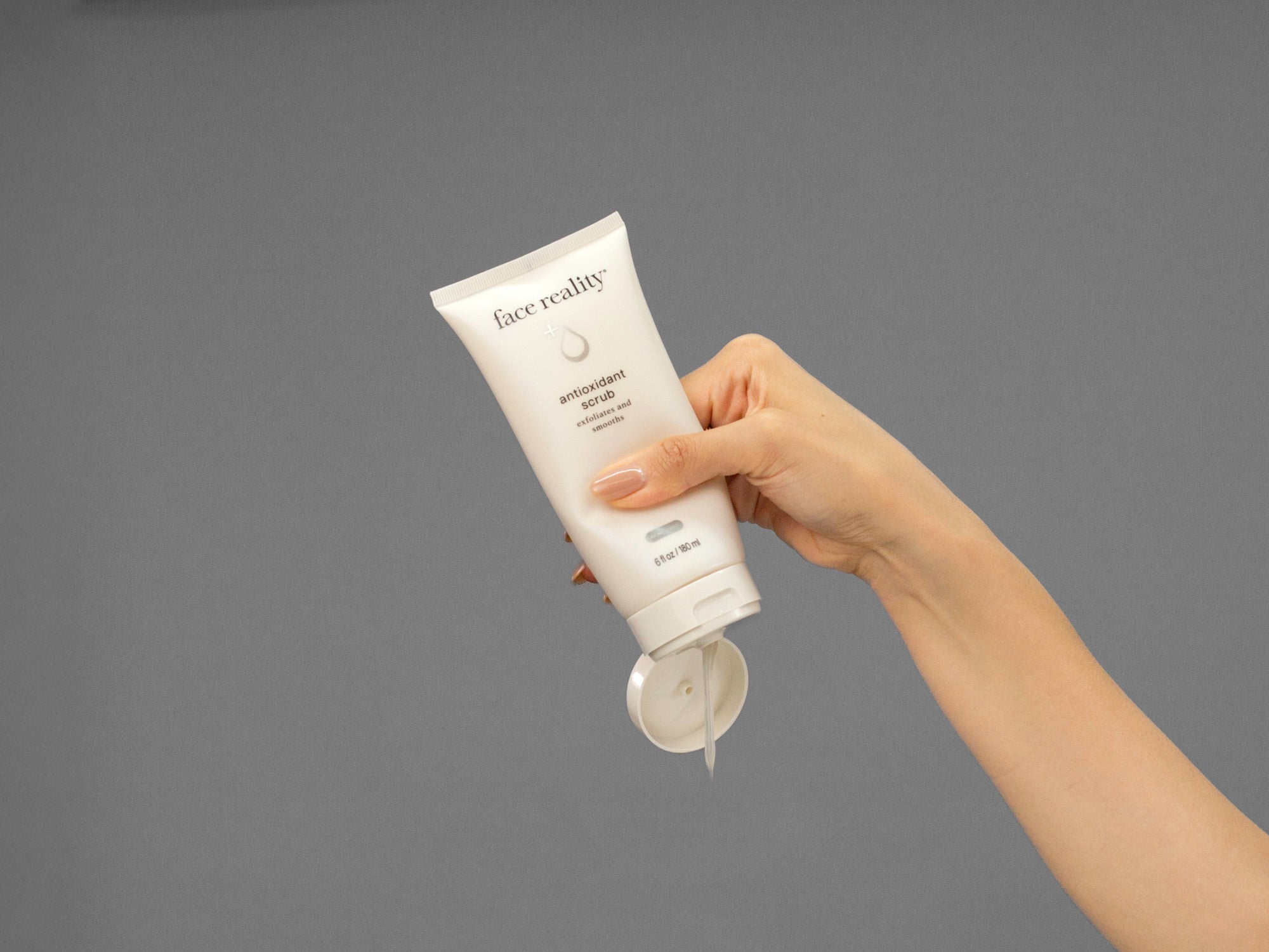 Closeup of Laziza from LAZ Skincare holding up a bottle of Face Reality Antioxidant Scrub