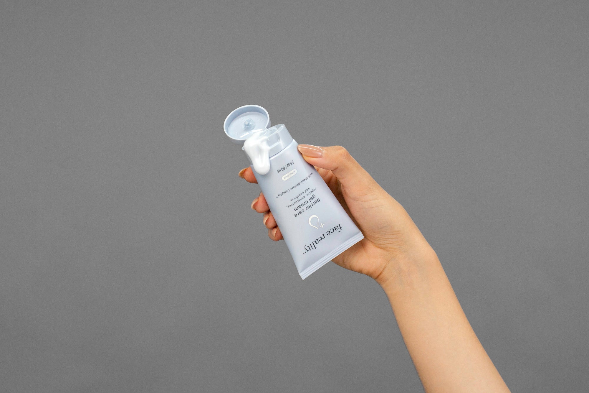 Closeup of Laziza from LAZ Skincare squeezing a tube of Face Reality Barrier Care Gel Cream in her hand