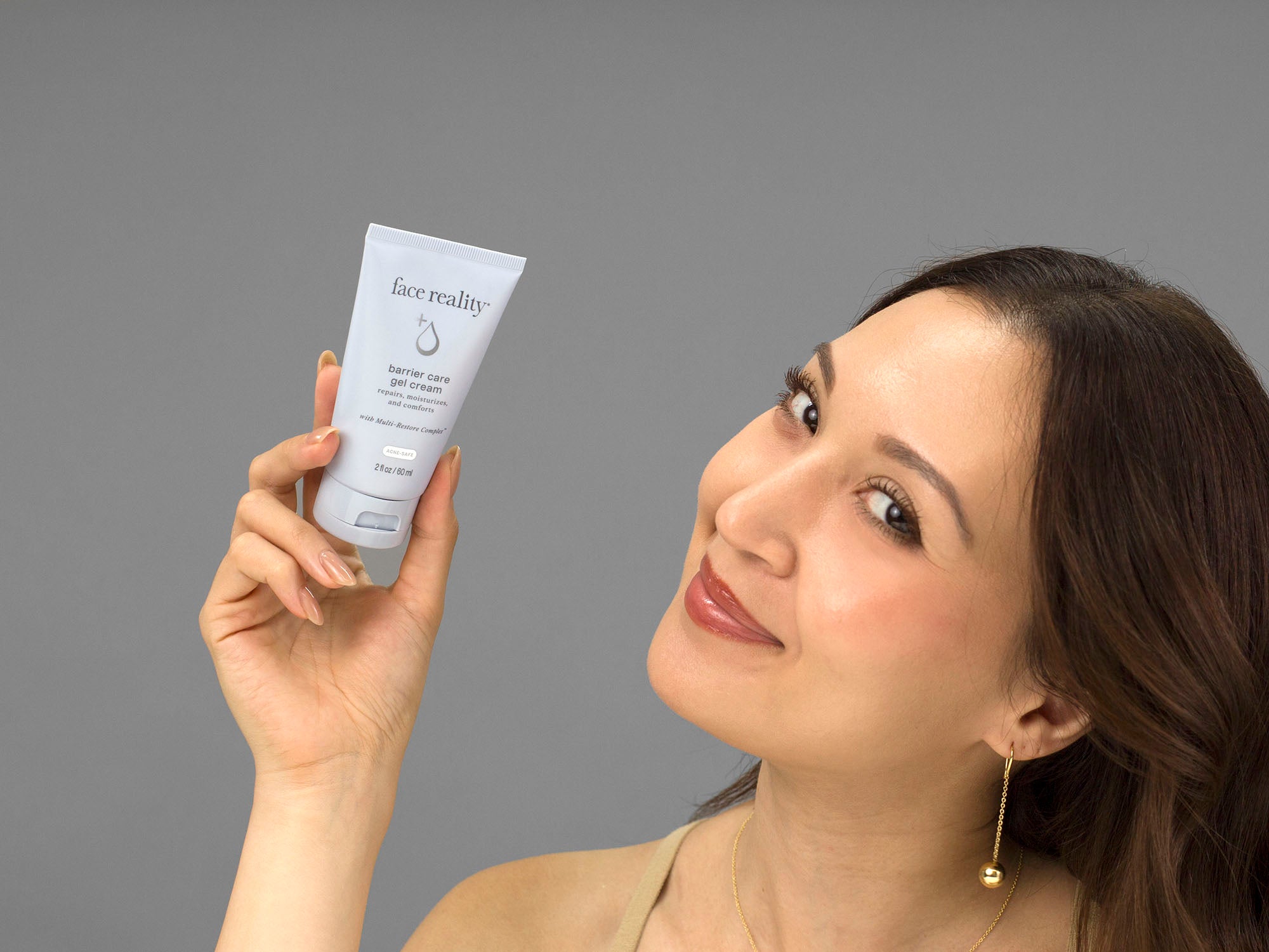 Laziza from LAZ Skincare holding a bottle of Face Reality Barrier Care Gel Cream up to her face