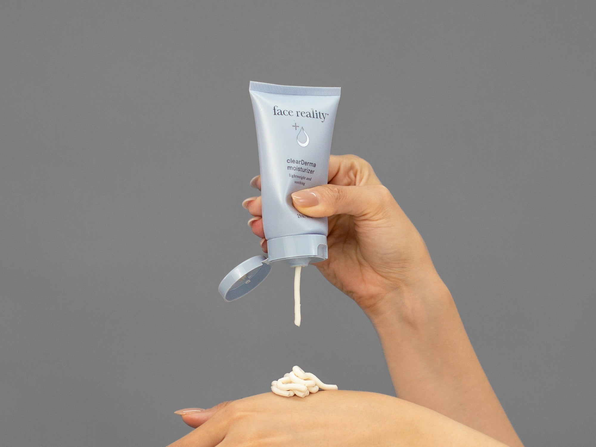 Closeup of Laziza from LAZ Skincare holding up a bottle of Face Reality Clearderma Moisturizer