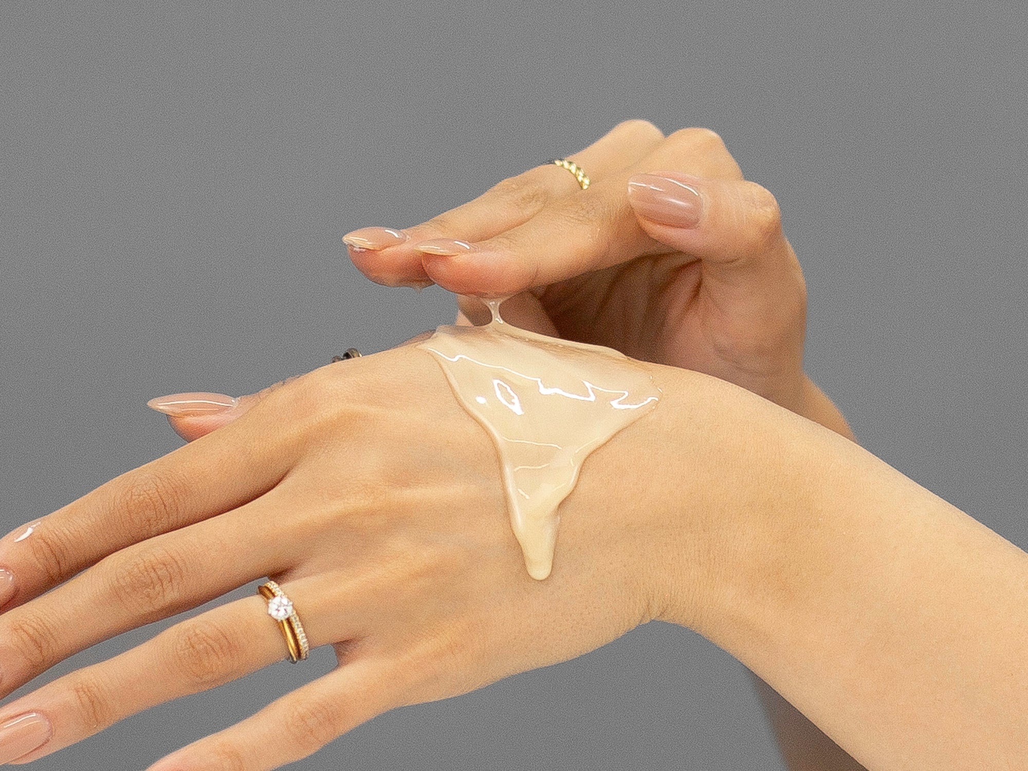 Laziza from LAZ Skincare demonstrating the texture and application of Face Reality GlowTone Corrective Serum on her hand