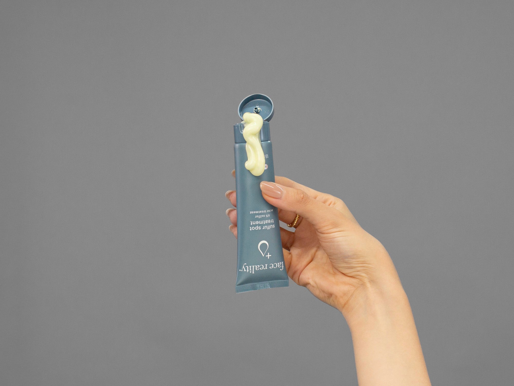 Closeup of Laziza from LAZ Skincare holding up a bottle of Face Reality Sulfur Spot Treatment