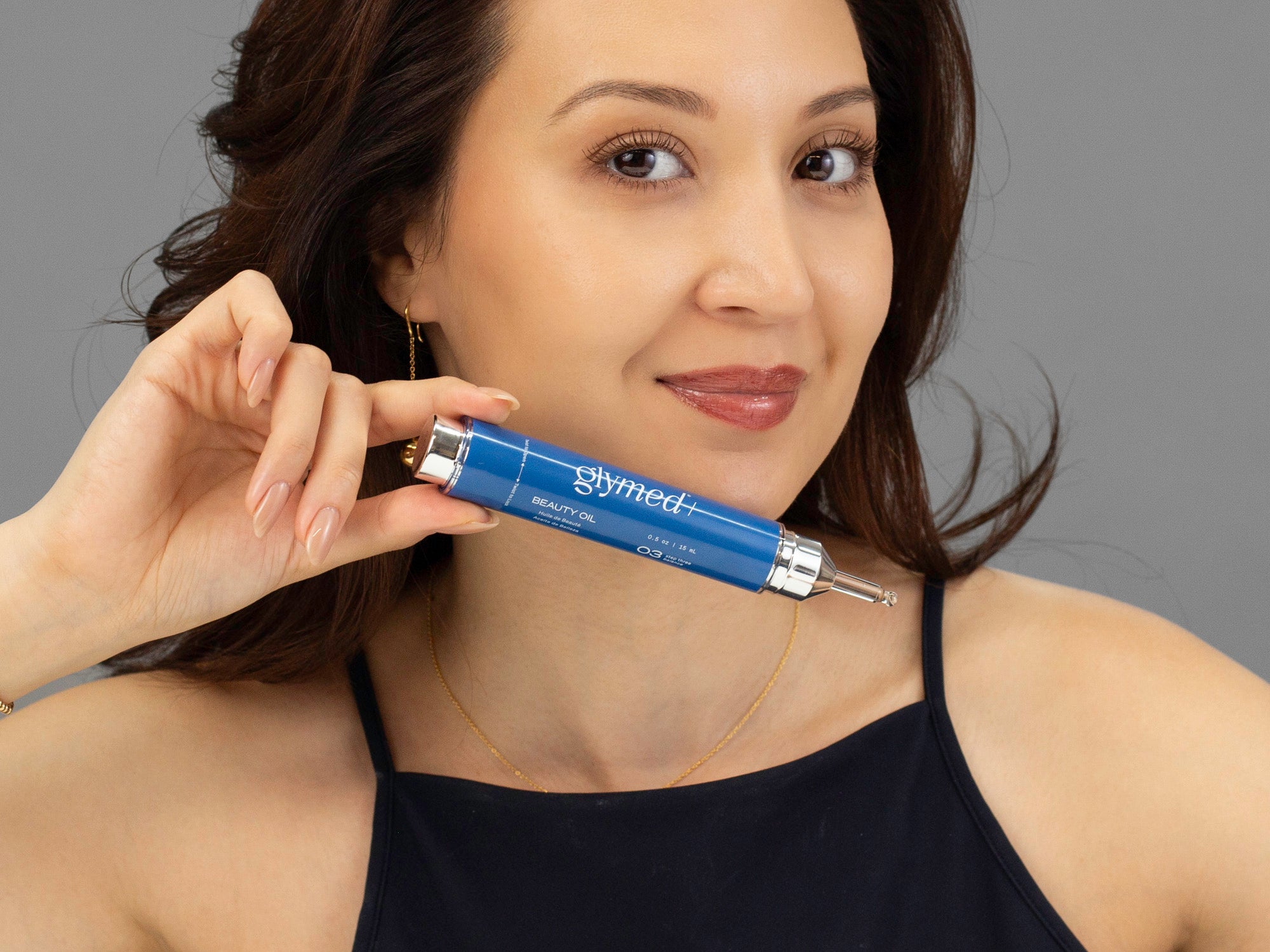 Closeup of Laziza from LAZ Skincare holding a bottle of GlyMed Beauty Oil up to her face