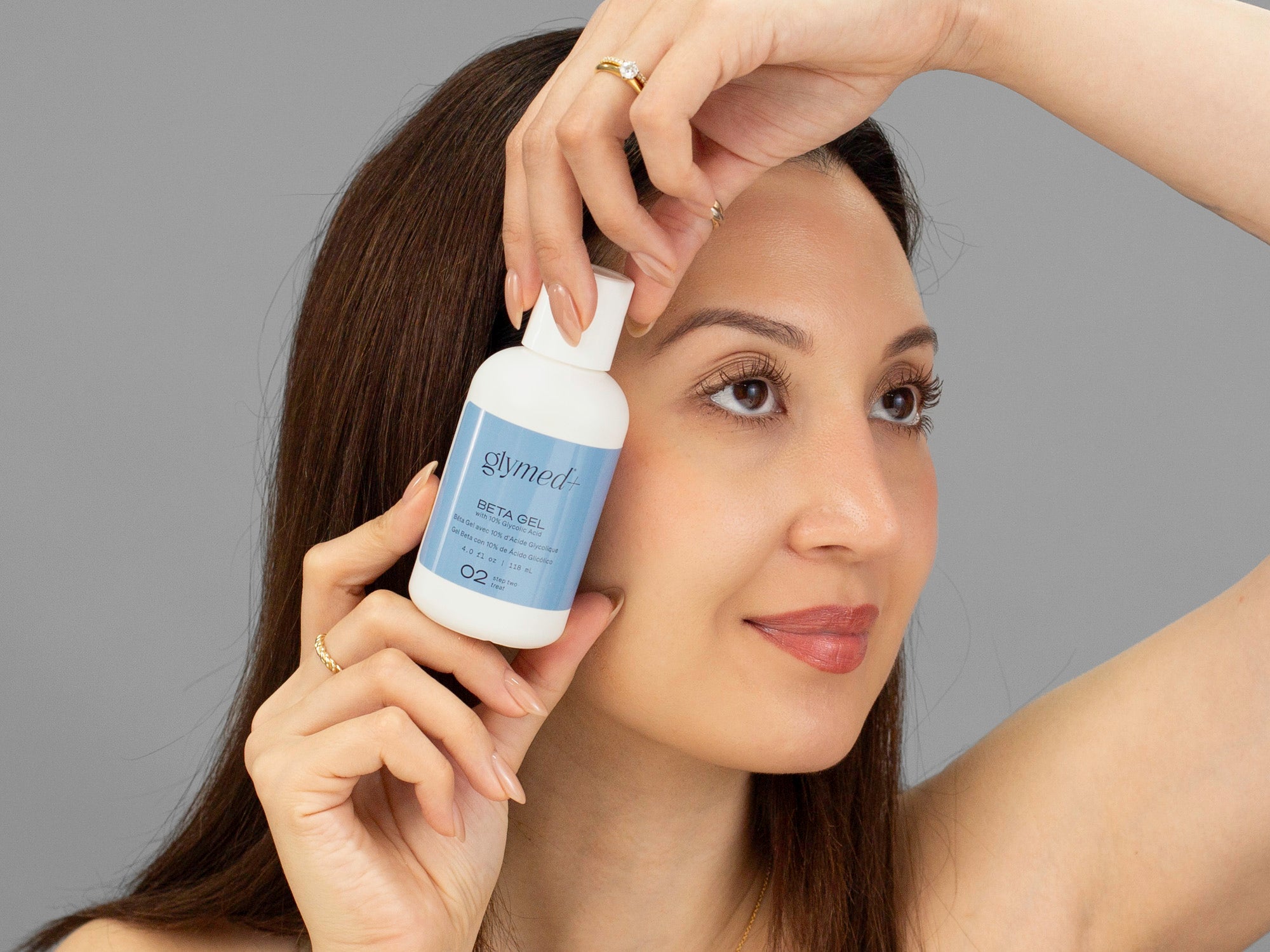 Laziza from LAZ Skincare holding a bottle of GlyMed Beta Gel up to her face