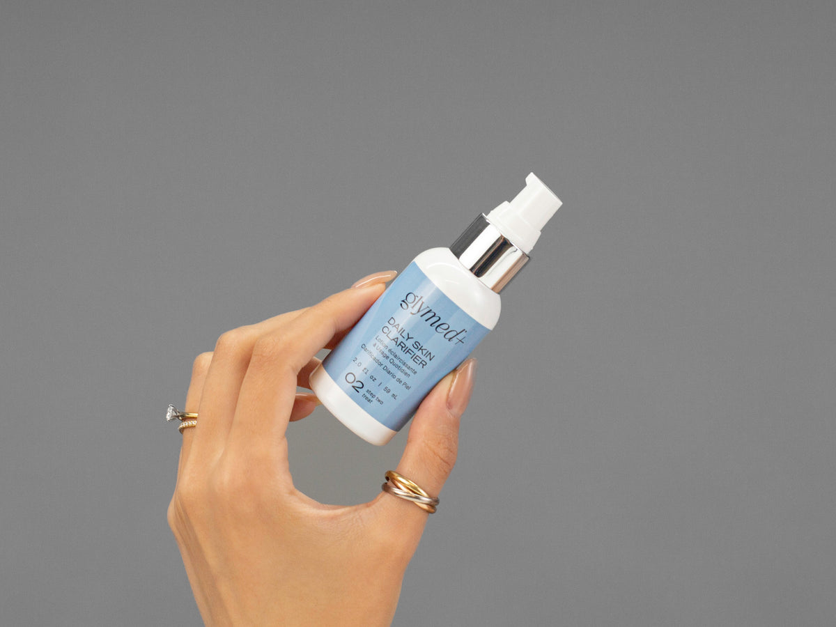 Closeup of Laziza from LAZ Skincare holding up a bottle of GlyMed Daily Skin Clarifier