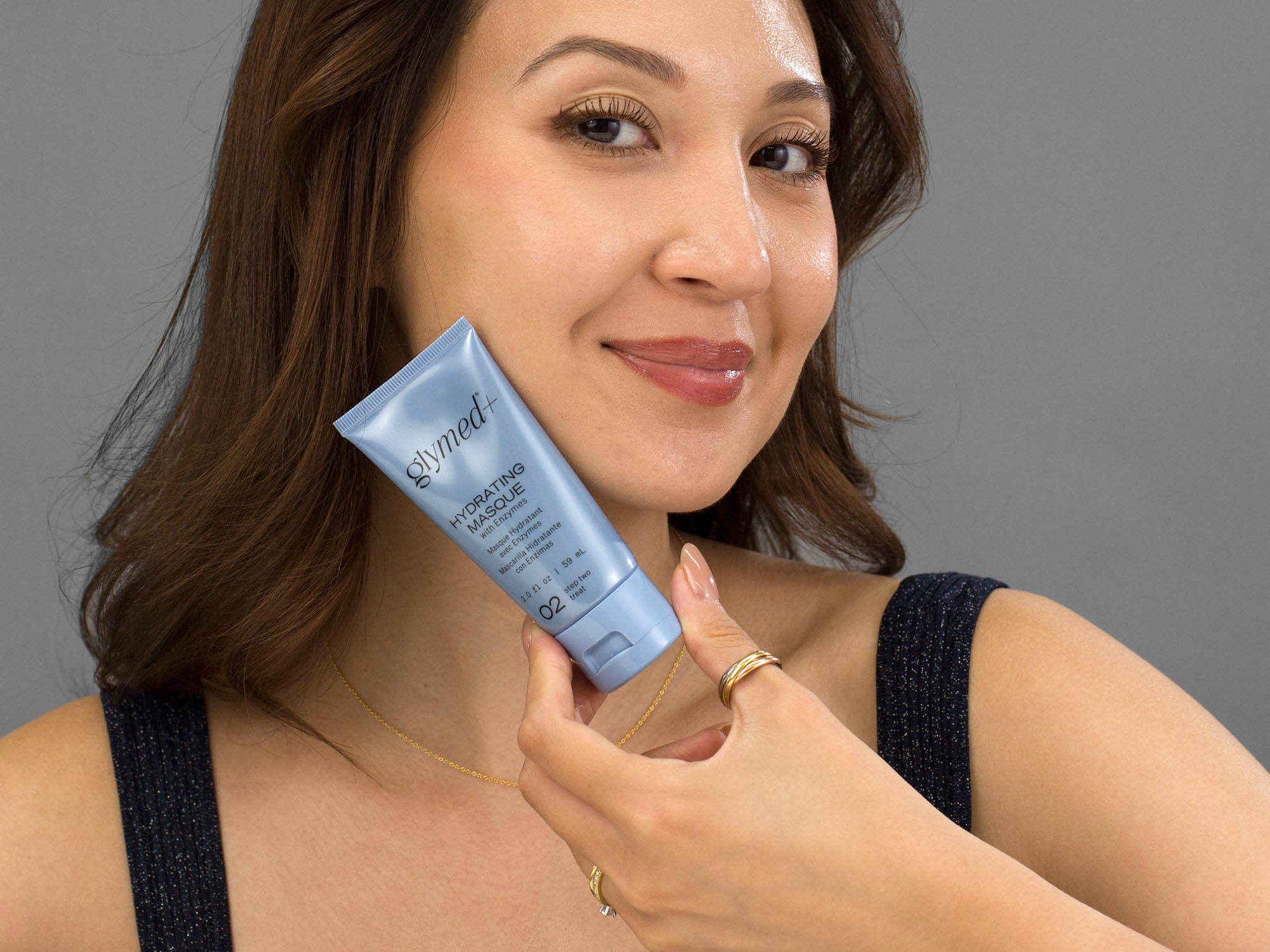 Laziza from LAZ Skincare holding a tube of GlyMed Hydrating Masque up to her face