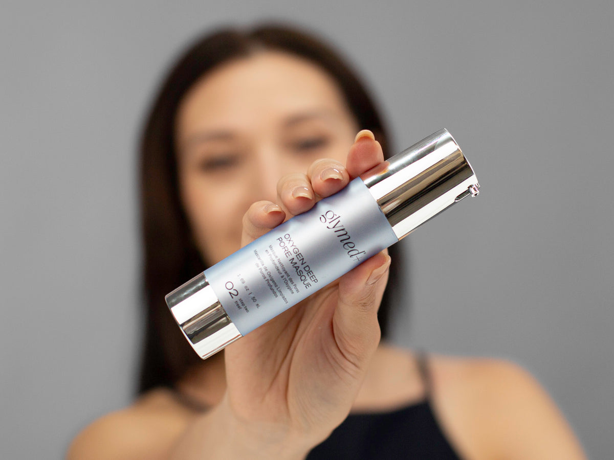 Laziza from LAZ Skincare holding a bottle of GlyMed Oxygen Deep Pore Masque up to her face