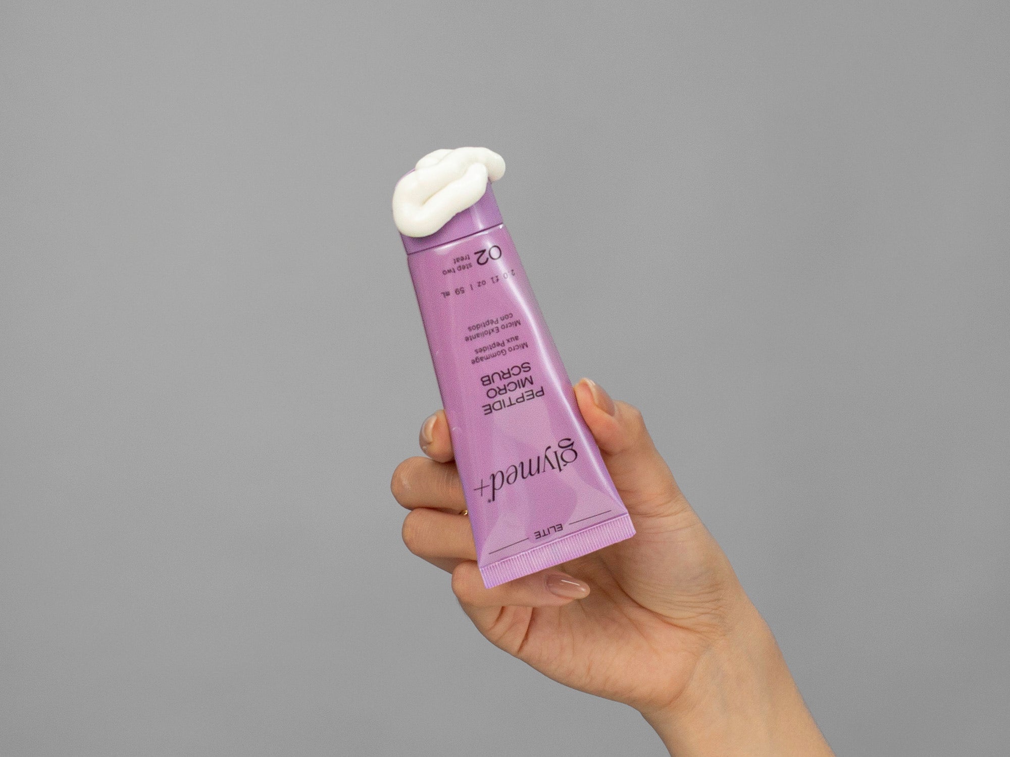 Closeup of Laziza from LAZ Skincare holding up a bottle of GlyMed Peptide Micro Scrub