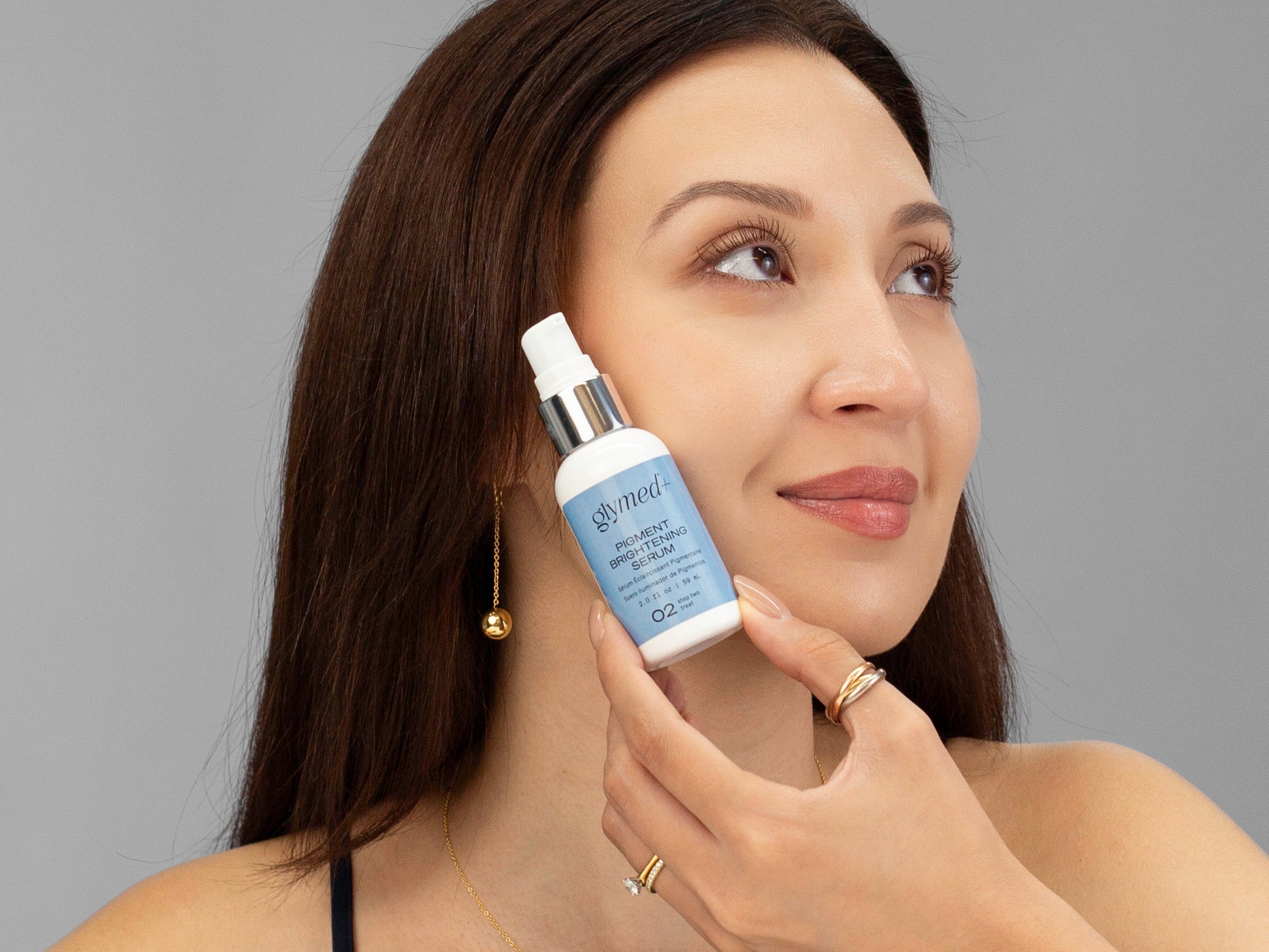 LAZ Skincare holding a bottle of GlyMed Pigment Brightening Serum up to her face