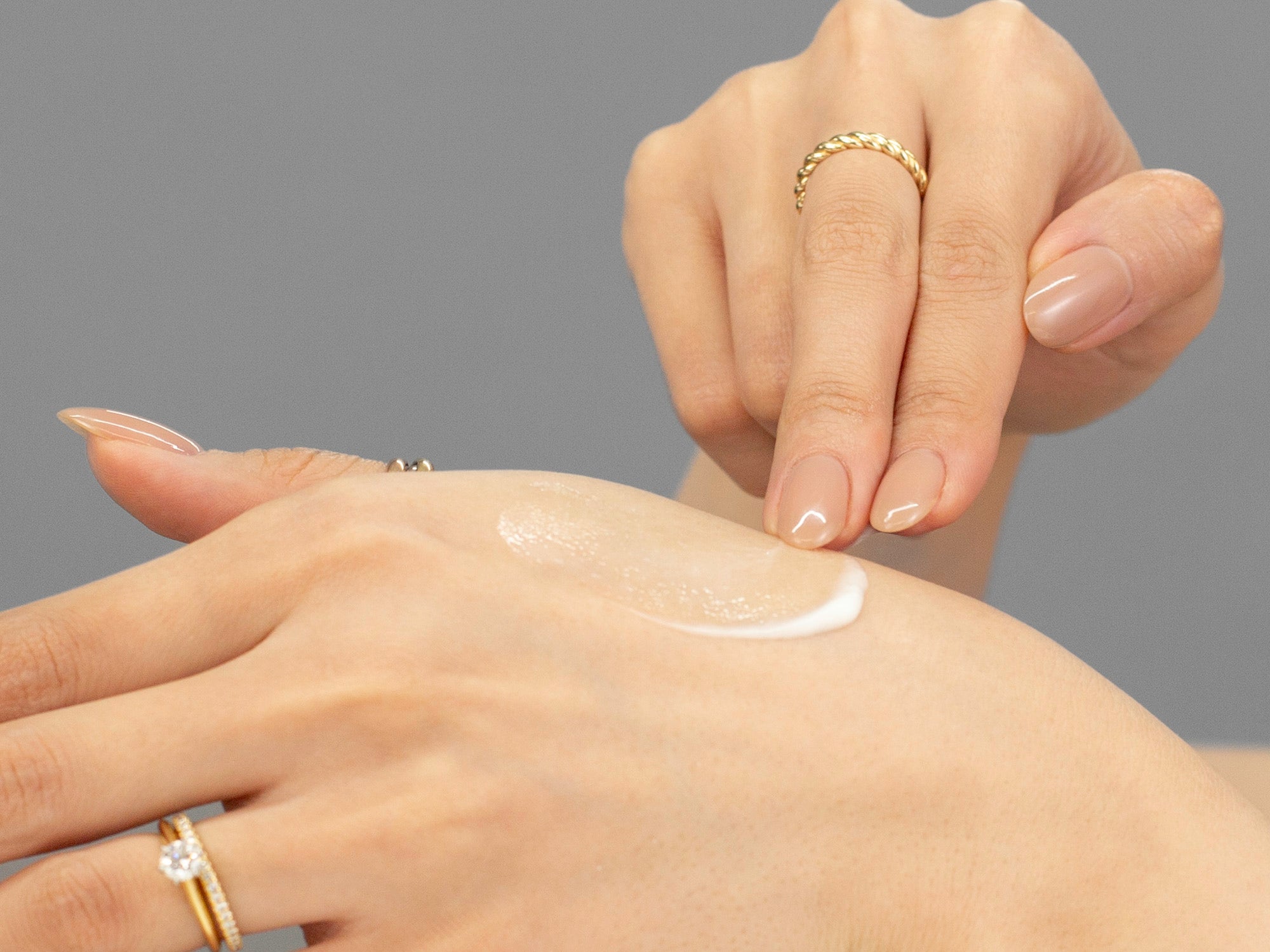 Laziza from LAZ Skincare demonstrating the texture and application of GlyMed Protective Skin Serum on her hand