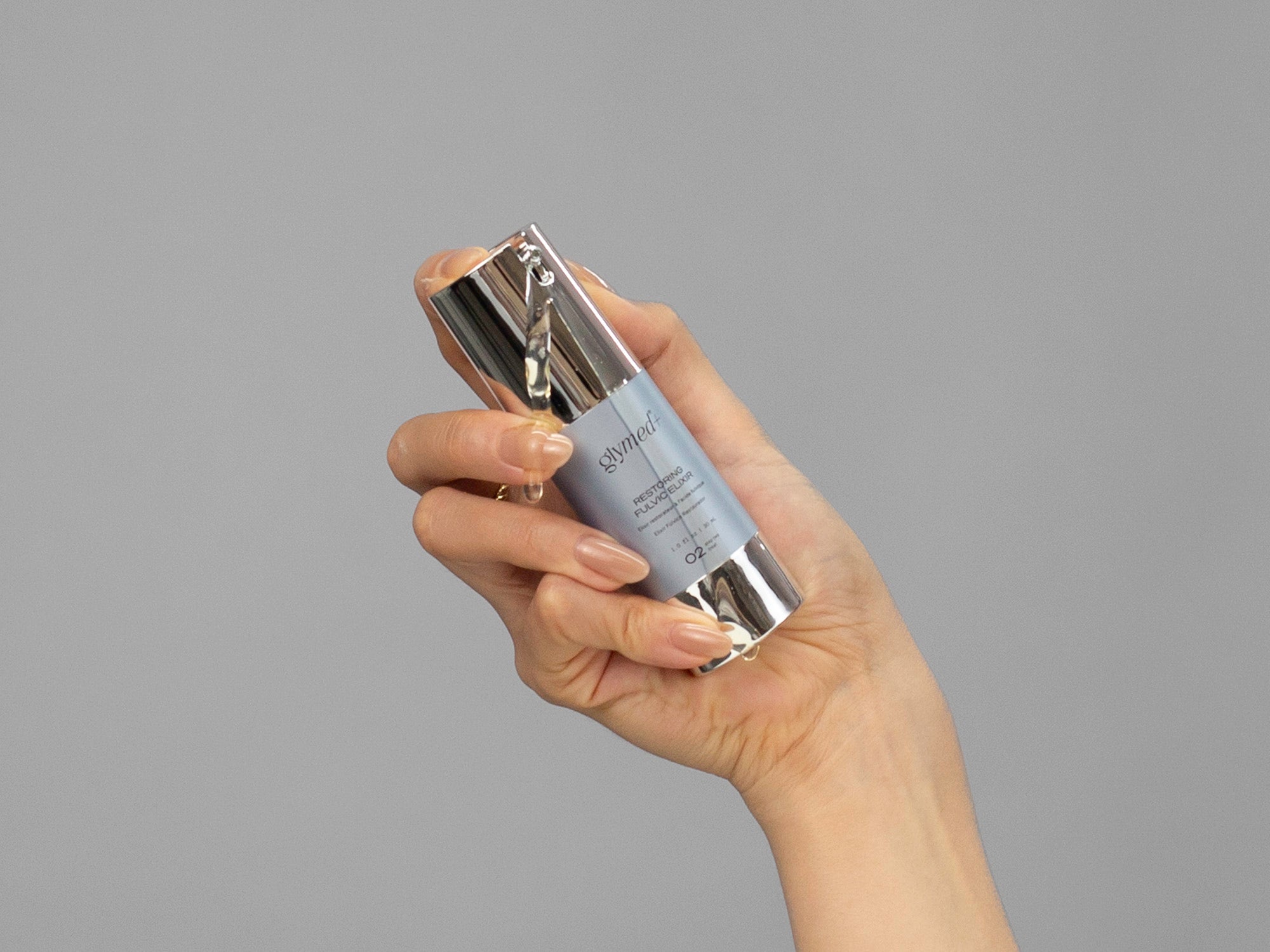 Closeup of Laziza from LAZ Skincare holding a bottle of GlyMed Restoring Fulvic Elixir in her hand