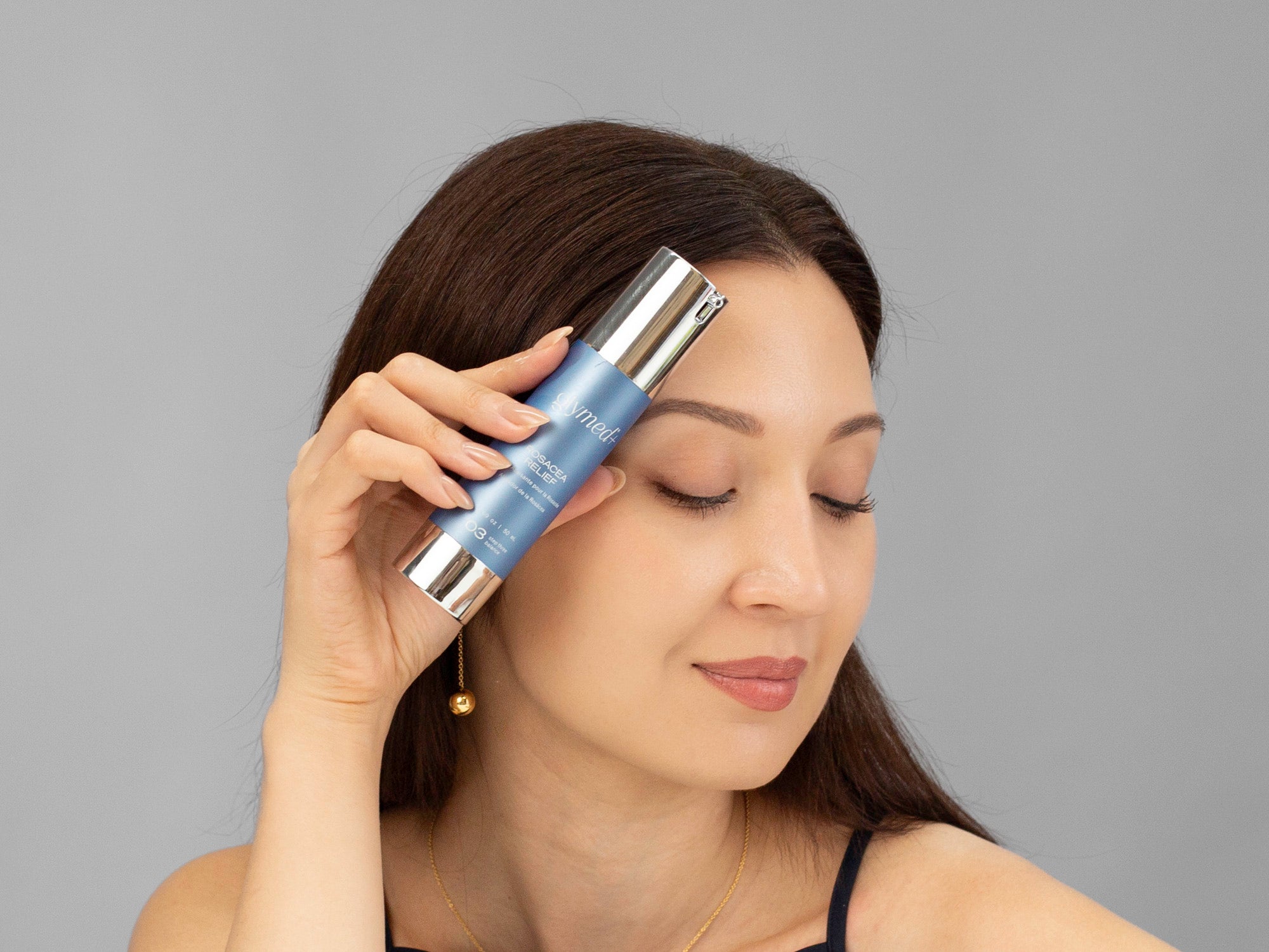 Laziza from LAZ Skincare holding a bottle of GlyMed Rosacea Relief up to her face