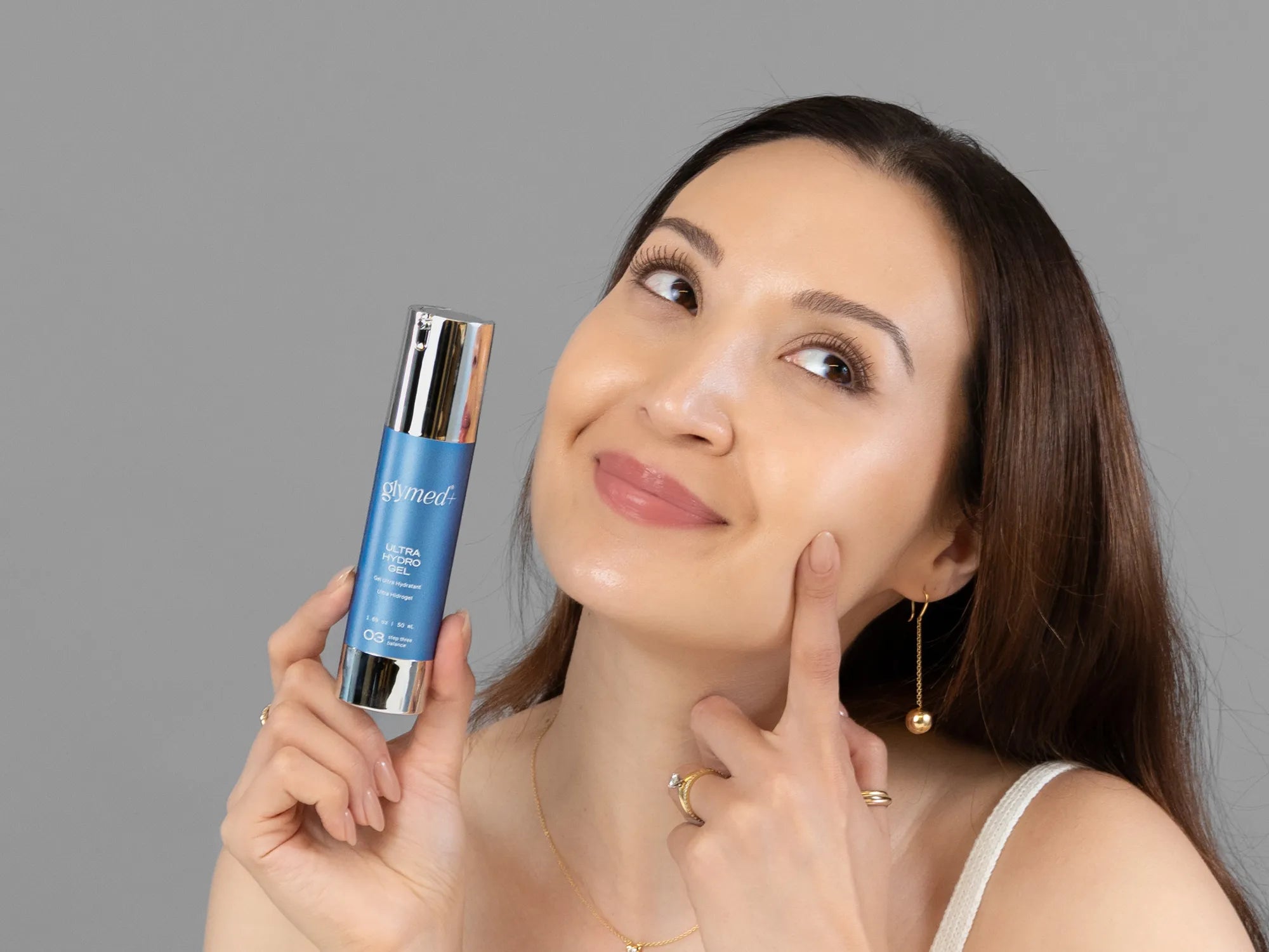 Laziza from LAZ Skincare holding a bottle of GlyMed Ultra Hydro Gel up to her face