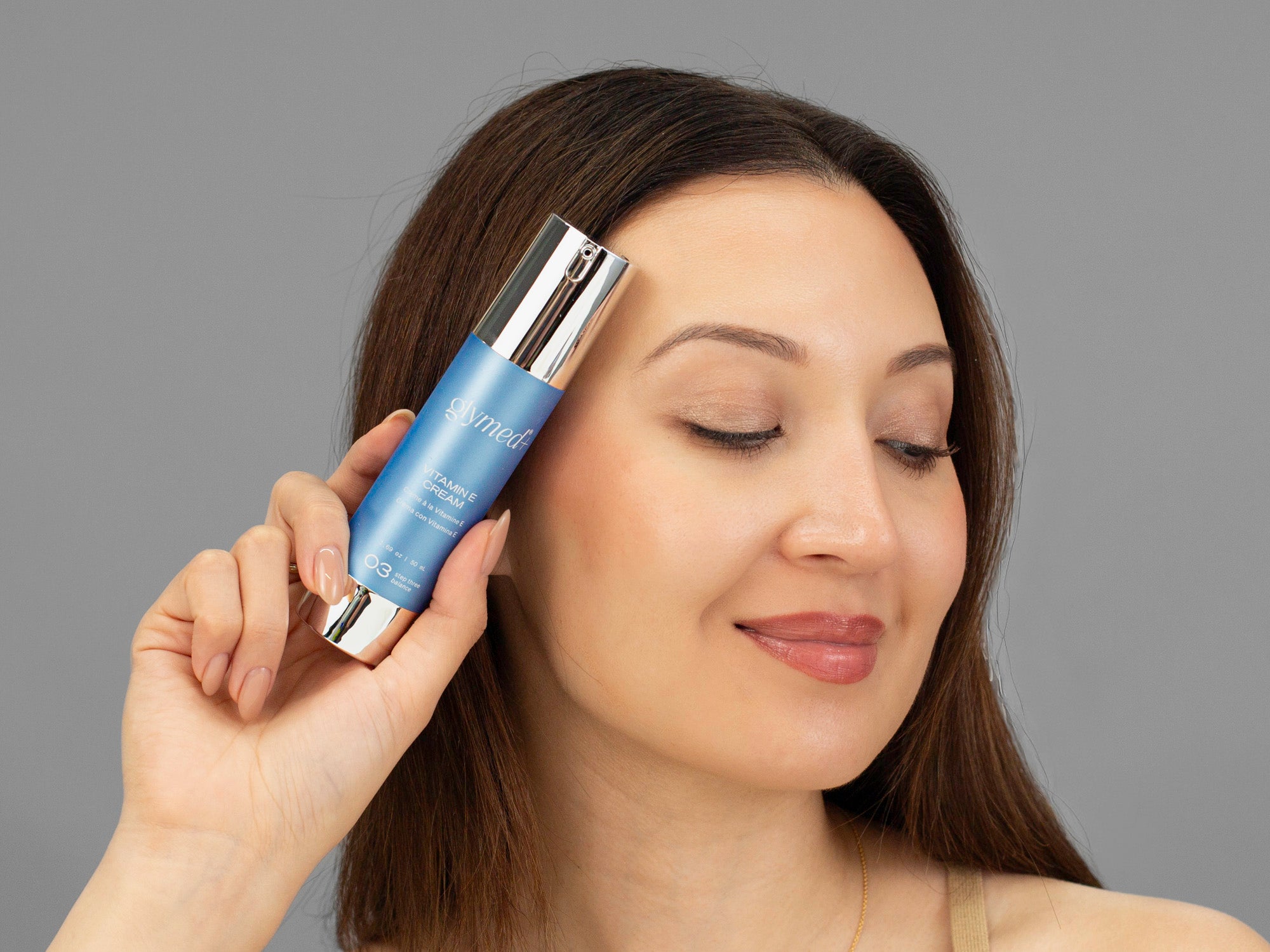 Laziza from LAZ Skincare holding a bottle of GlyMed Vitamin E Cream up to her face
