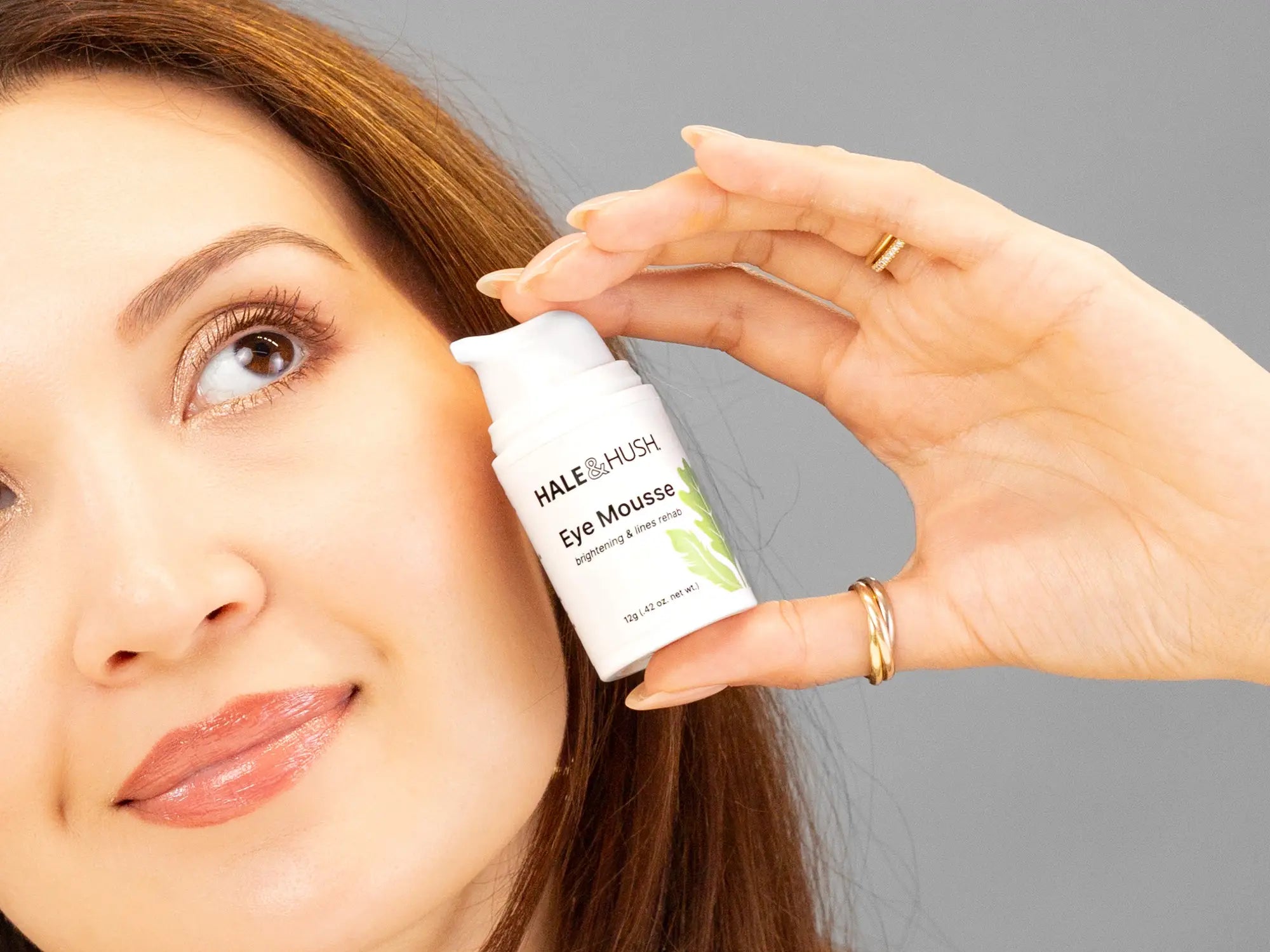 Laziza from LAZ Skincare holding a bottle of Hale & Hush Eye Mousse up to her face