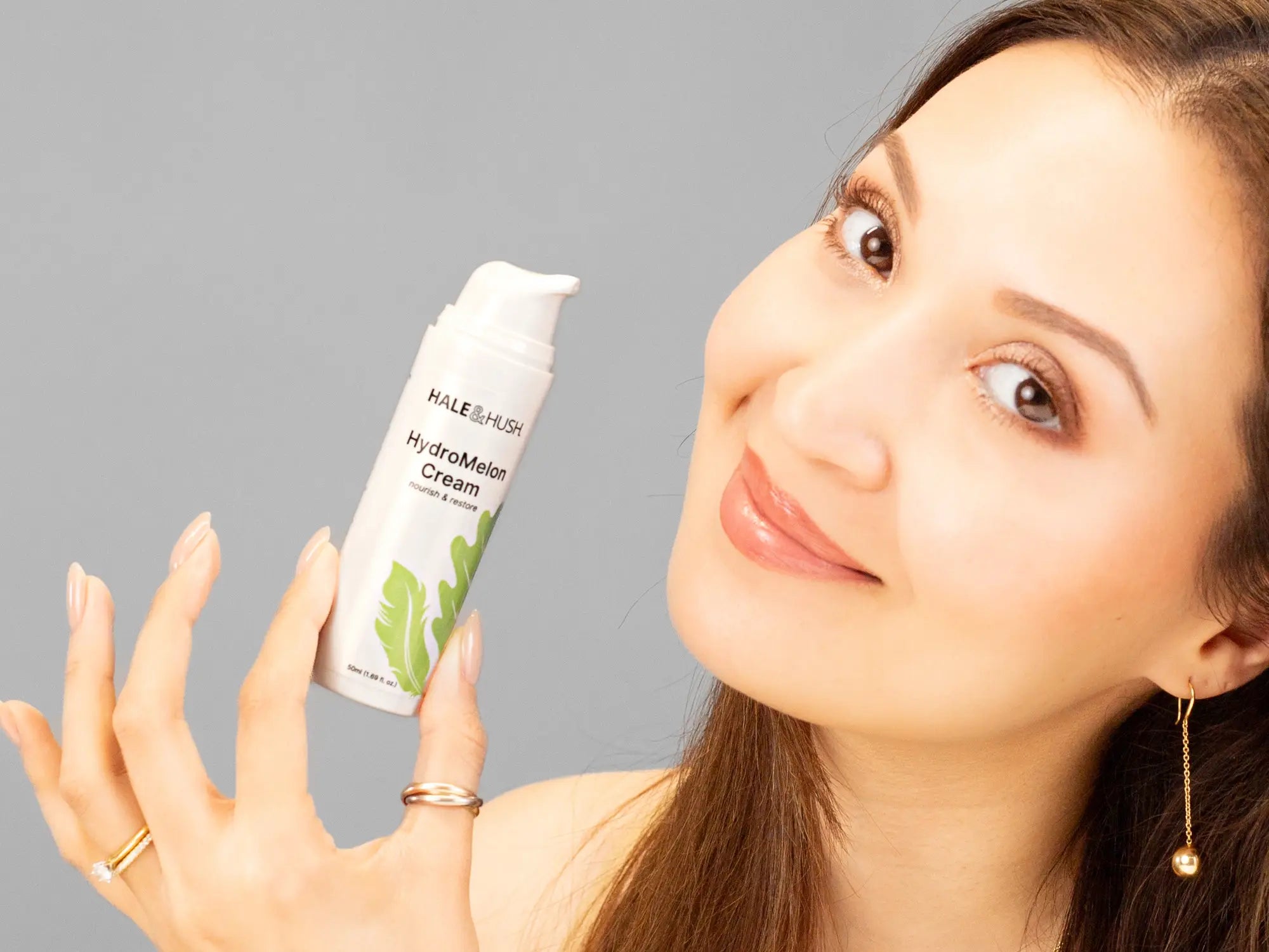 Laziza from LAZ Skincare holding a bottle of Hale & Hush HydroMelon Cream up to her face