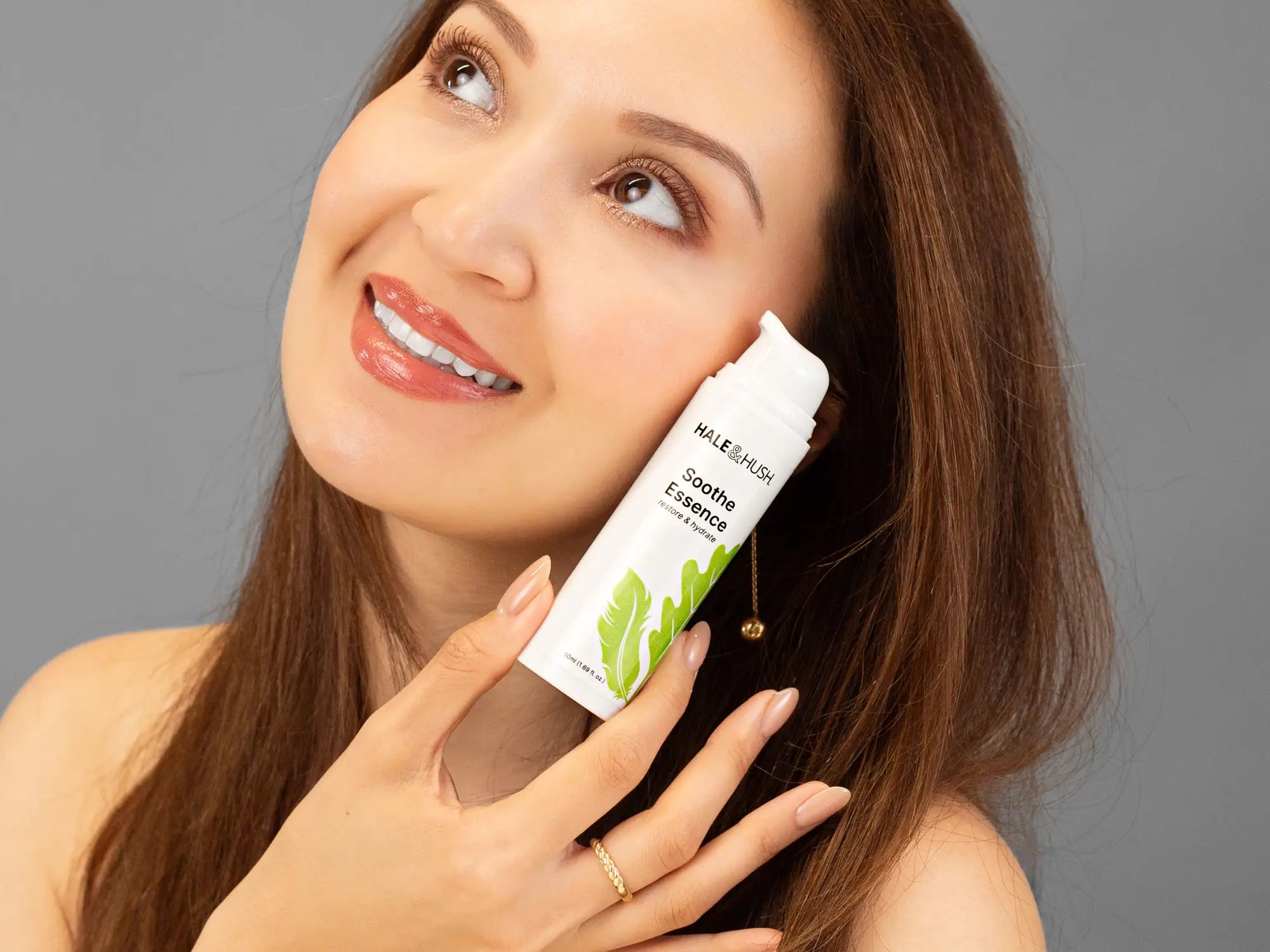 Laziza from LAZ Skincare holding a bottle of Hale & Hush Soothe Essence Serum up to her face