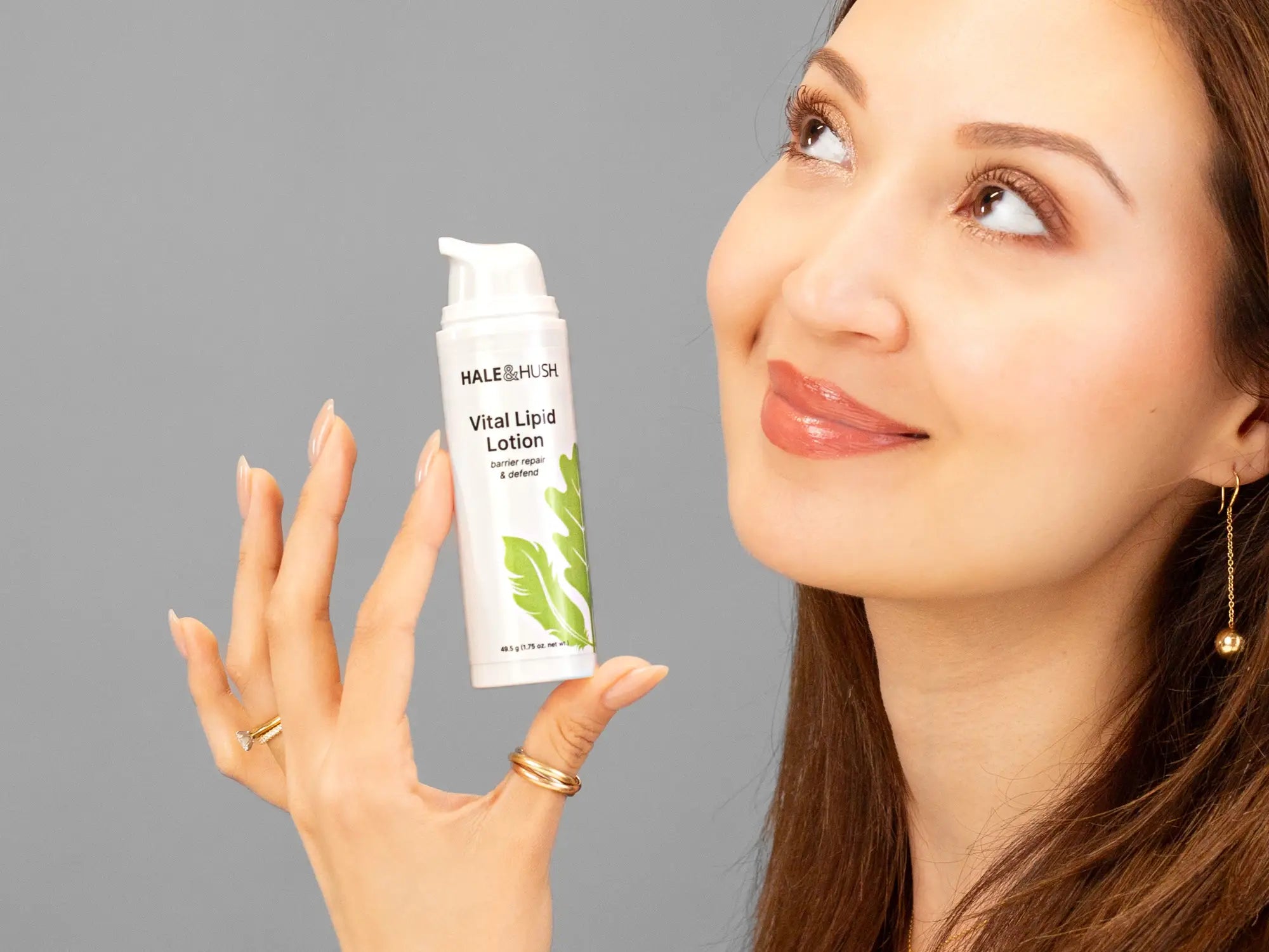 Laziza from LAZ Skincare holding a bottle of Hale & Hush Vital Lipid Lotion up to her face