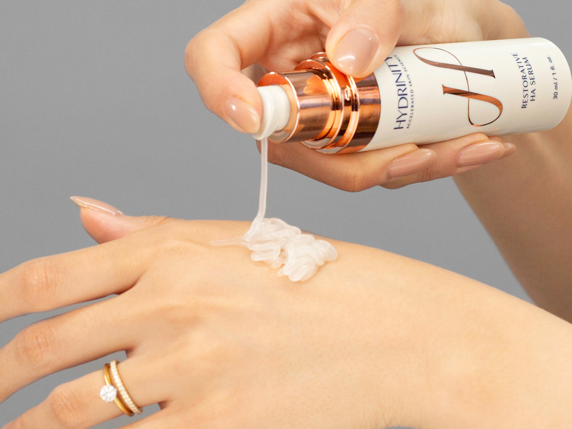 Closeup of Laziza from LAZ Skincare applying Hydrinity Resorative HA Serum to her hand